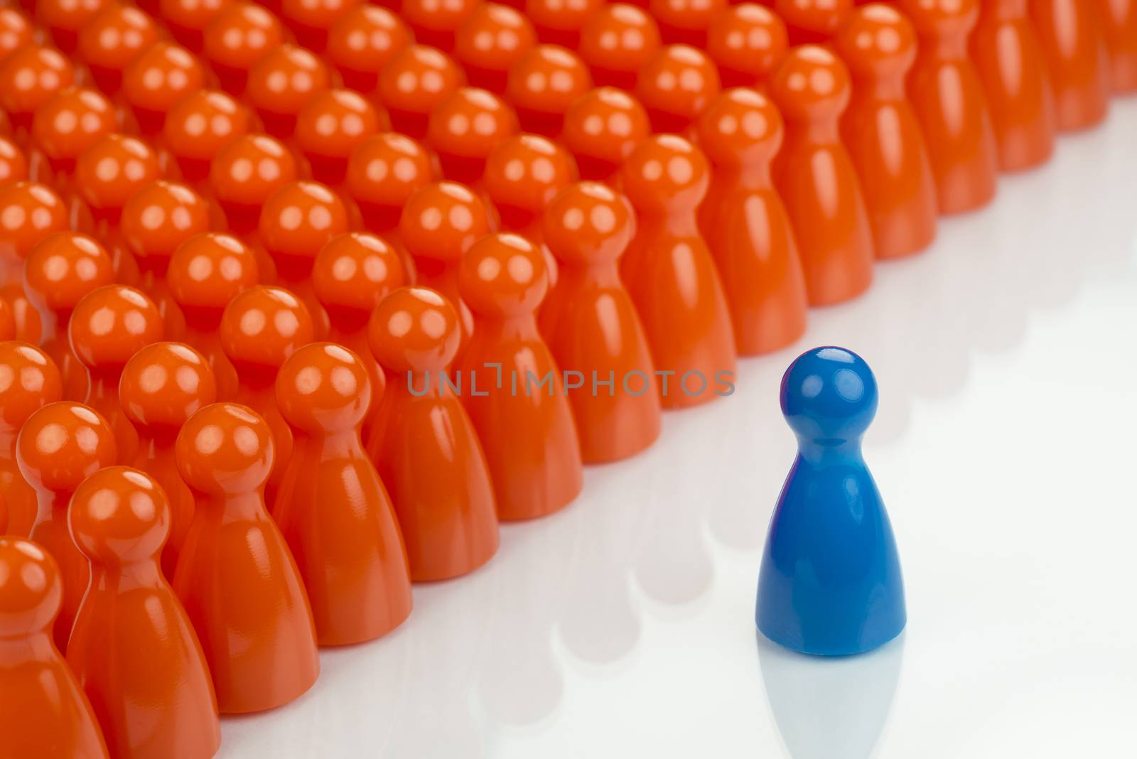 Conceptual orange game pawns and a blue play pawn by Tofotografie