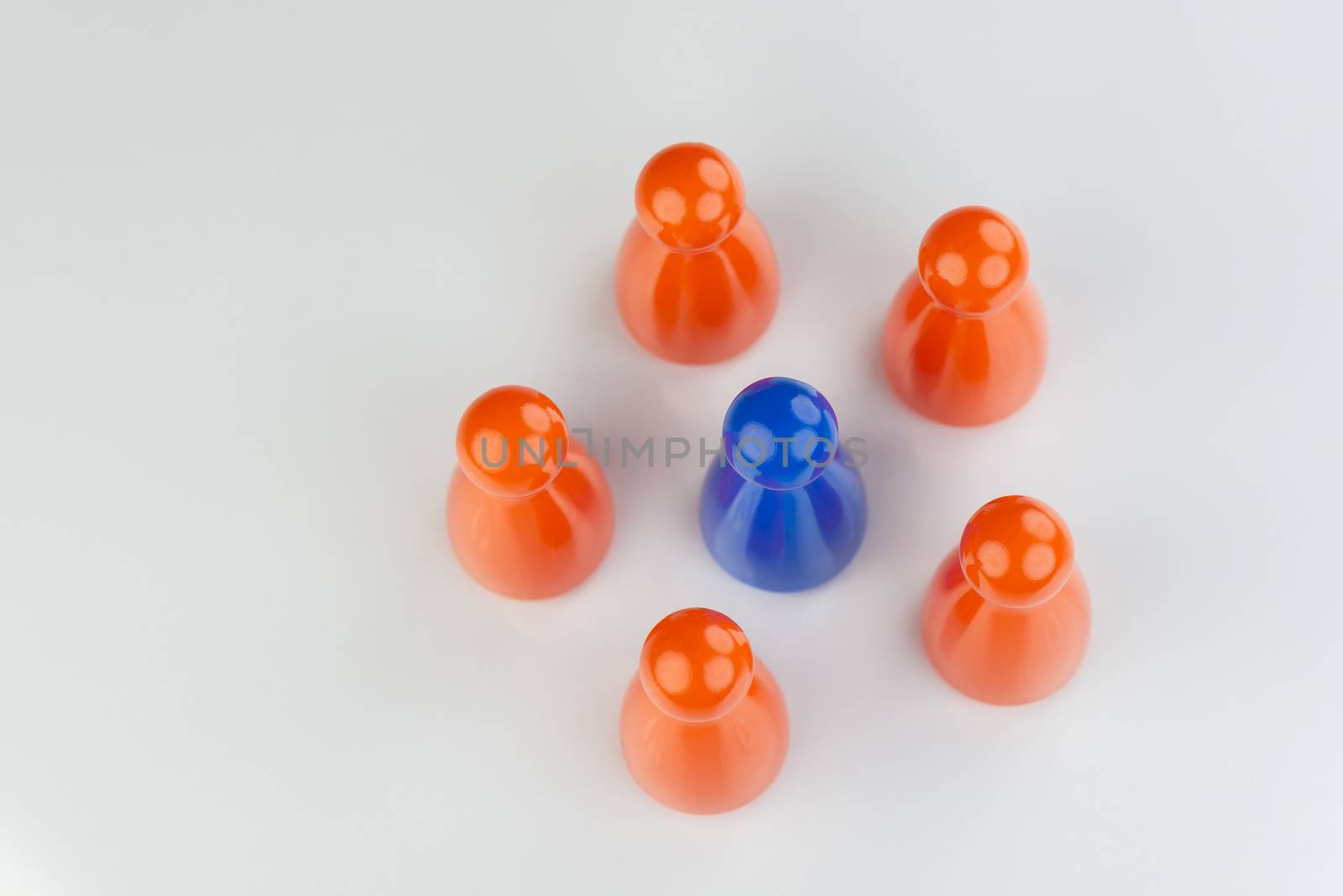 Conceptual orange game pawns and a blue play pawn  by Tofotografie