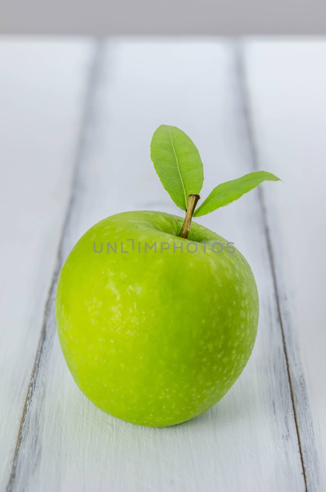 Ripe green apple with leaf  on a wooden background