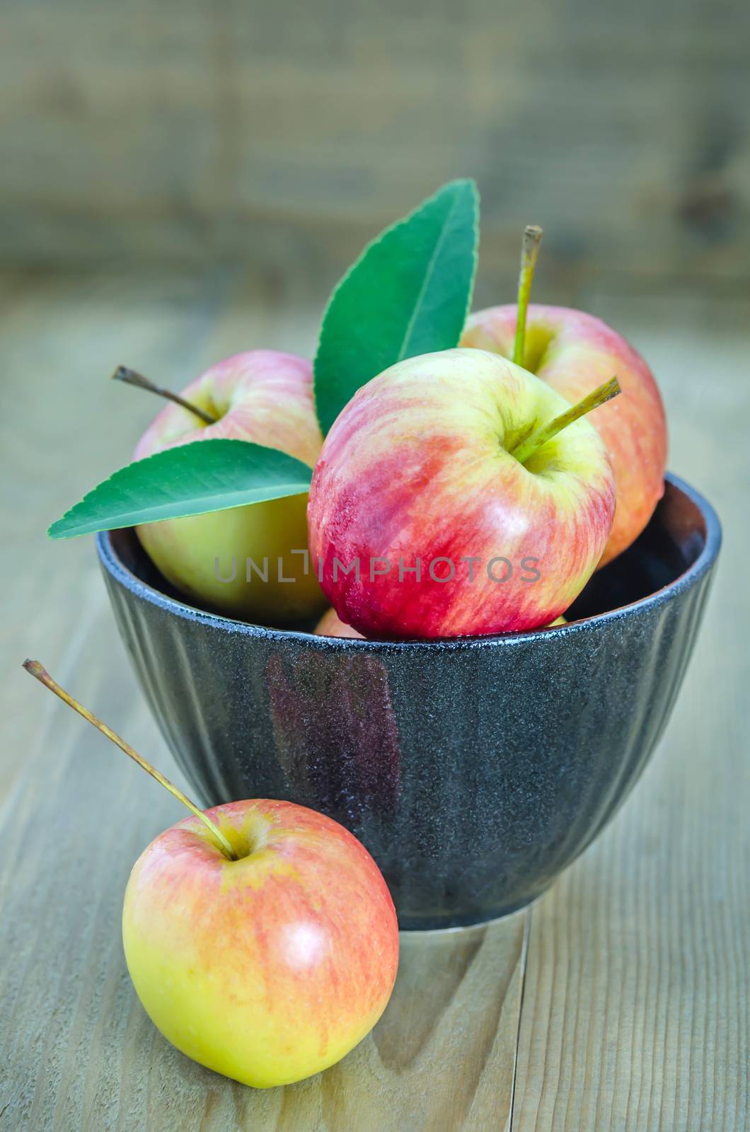 Red and yellow apple with black bowl by rakratchada