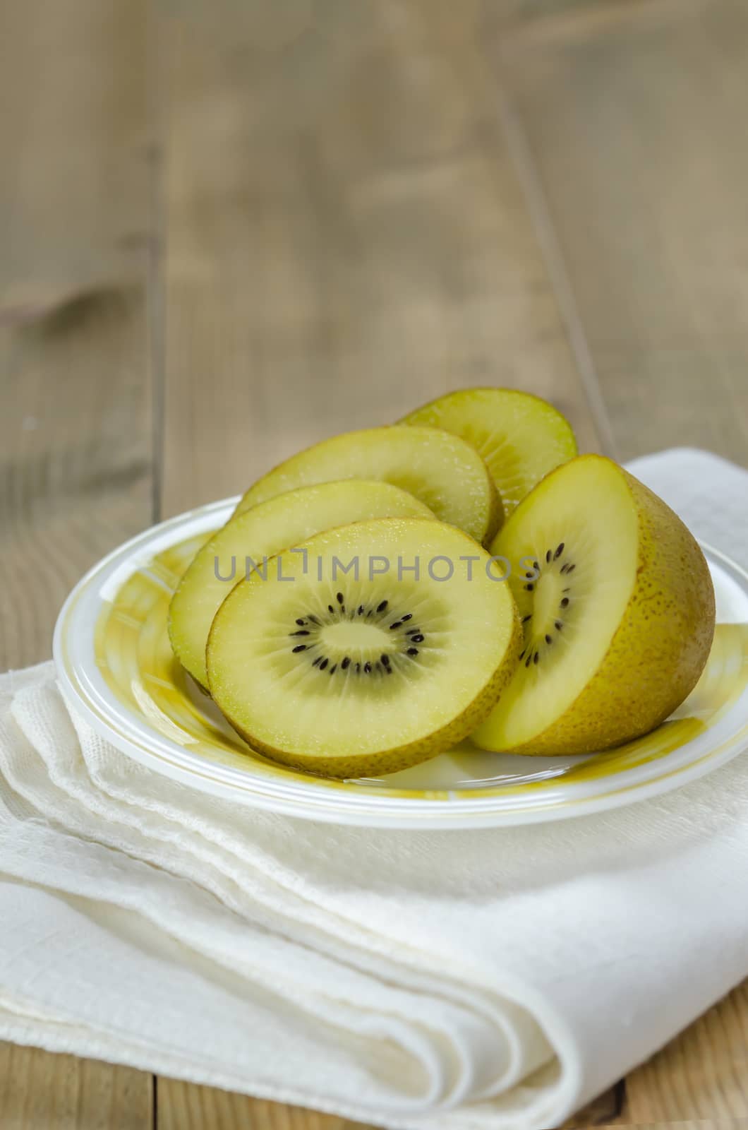 golden kiwi fruit and sliced on dish over wooden background