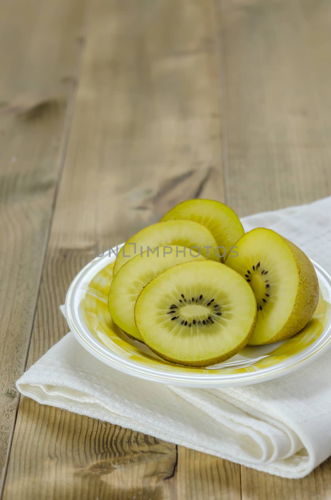 golden kiwi fruit and sliced on dish over wooden background