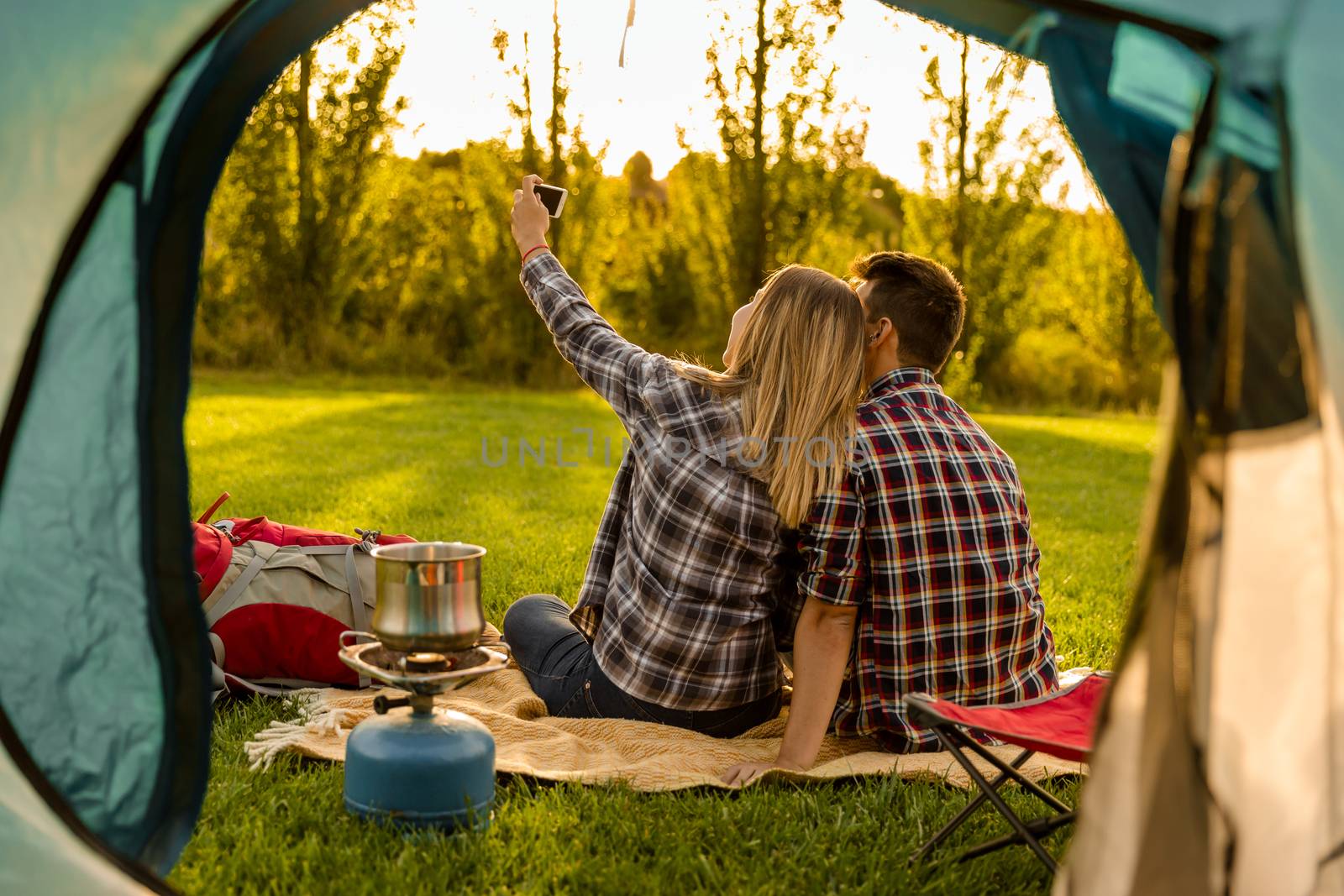 Shot of a happy couple camping on the nature and making a selfie