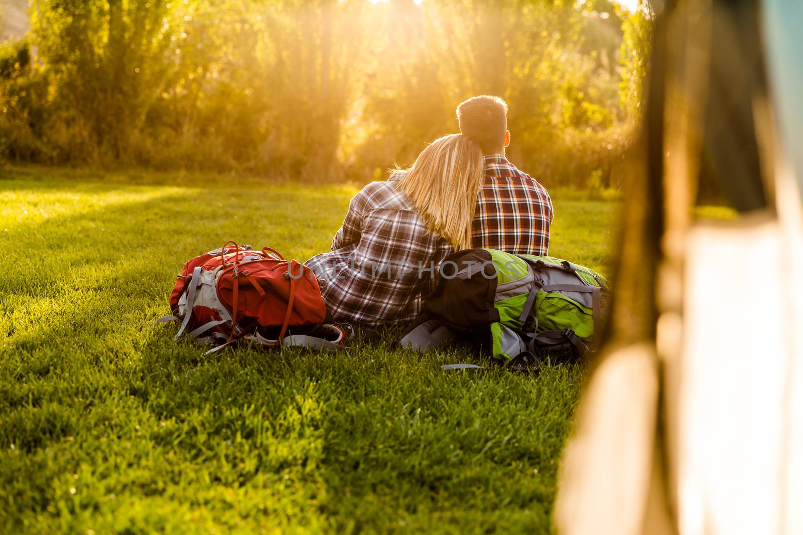 Young couple with backpacks sitting on the grass