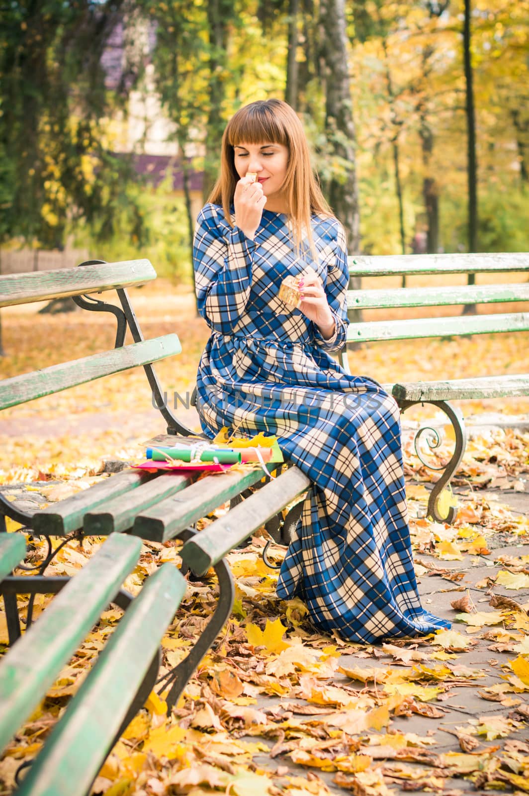 beautiful, dreamy girl with long straight hair in a blue long dress in the park in autumn