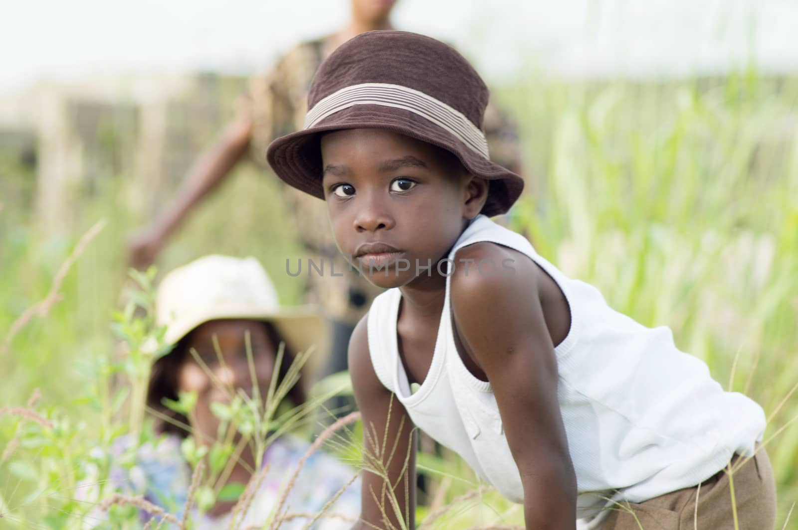 a child playing with the grass, her mother and annt in the background.