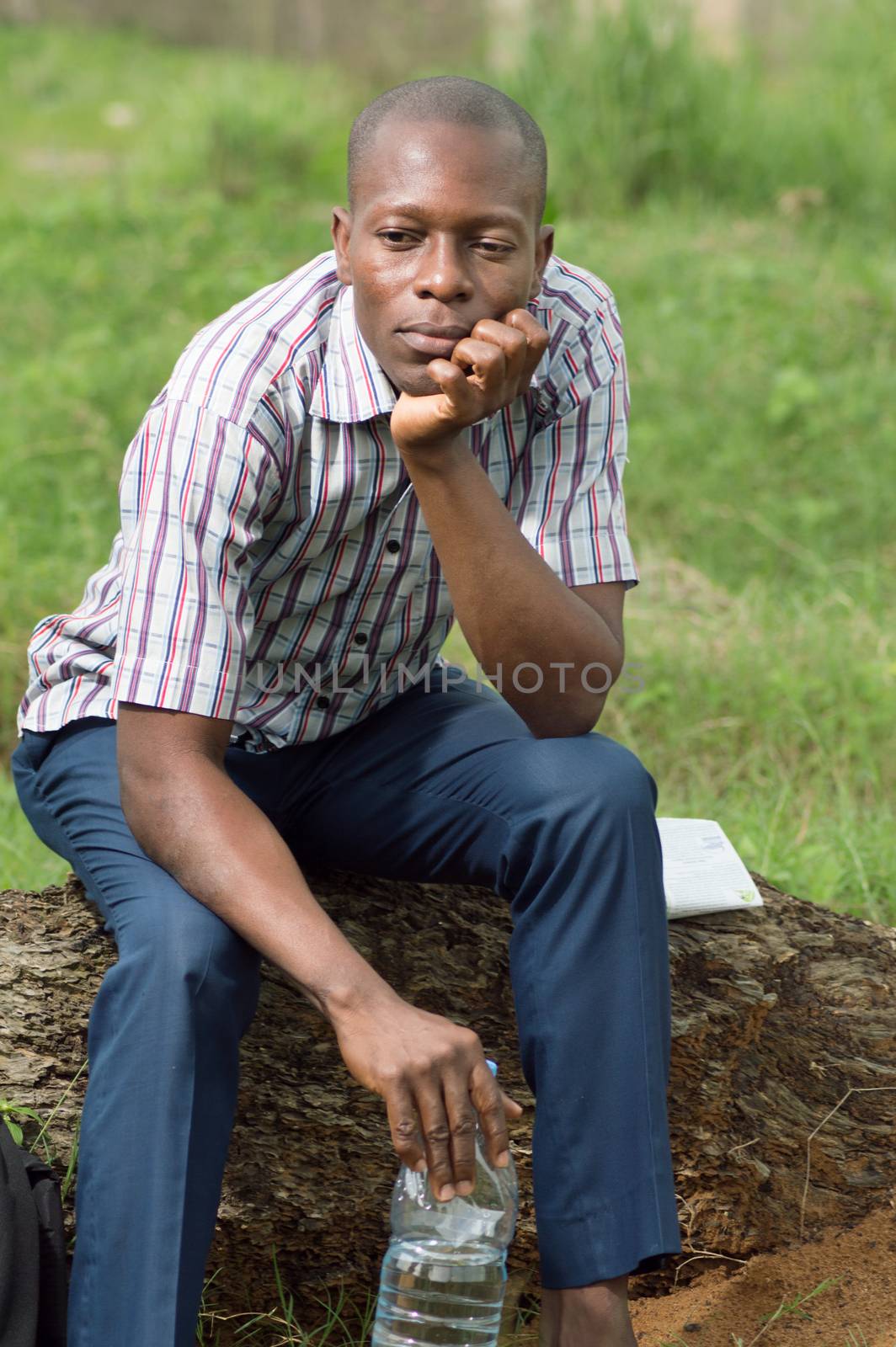 This tired young man , sits on a tree trunk very thoughtful.