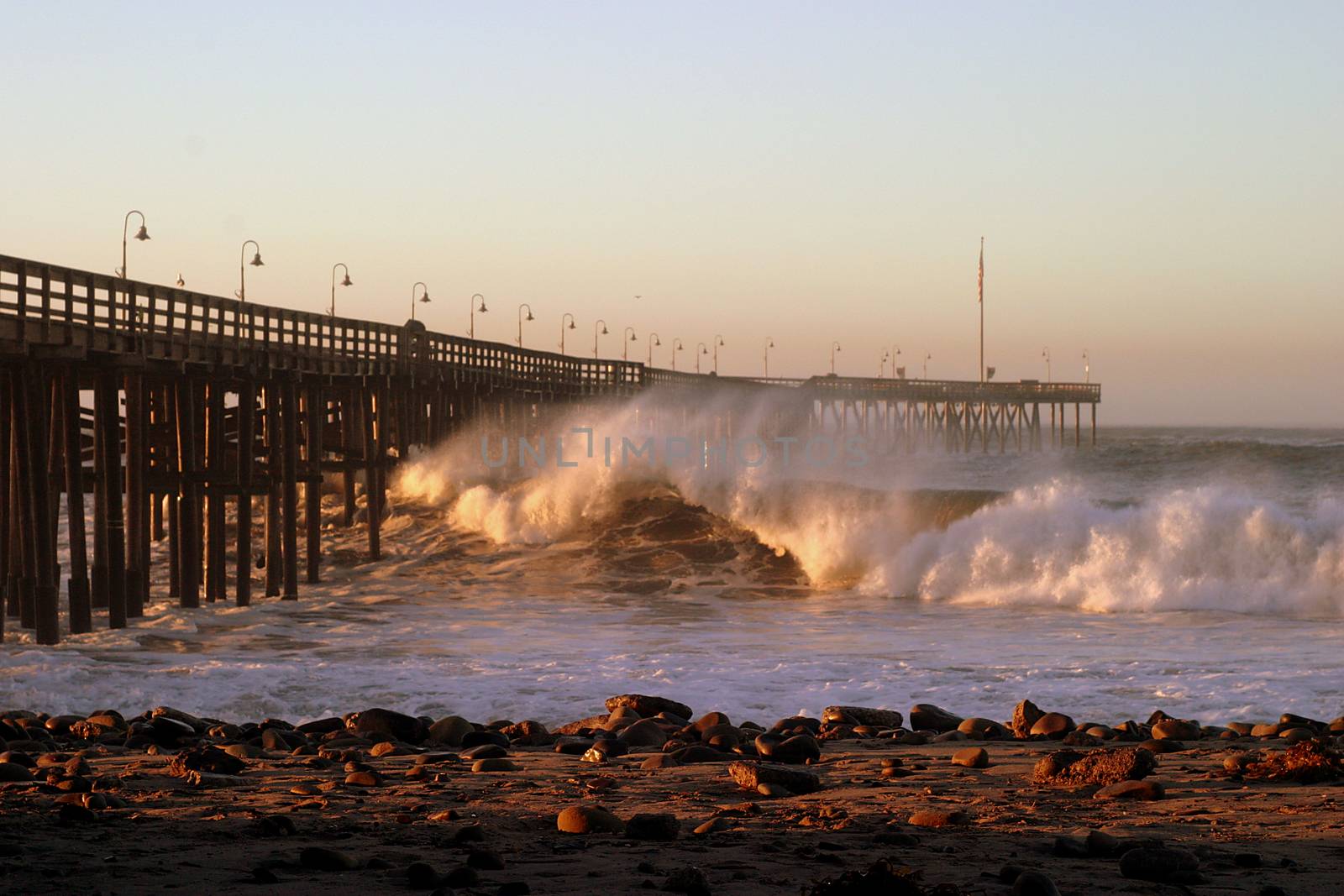 Ocean waves throughout at storm crashing into the wooden Ventura pier.