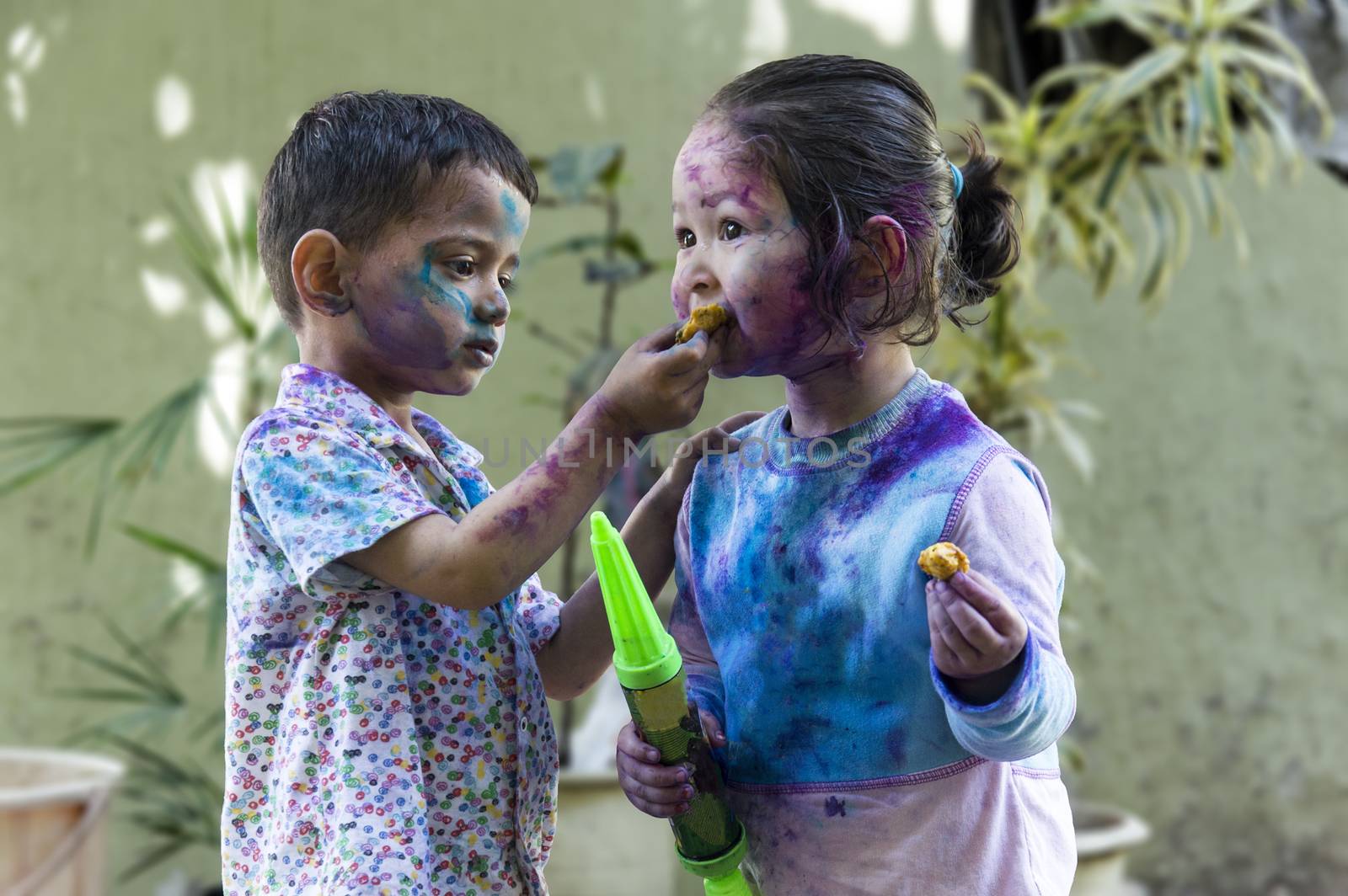 Brother and sister with their face smeared with colors celebrating Holi festival in India.