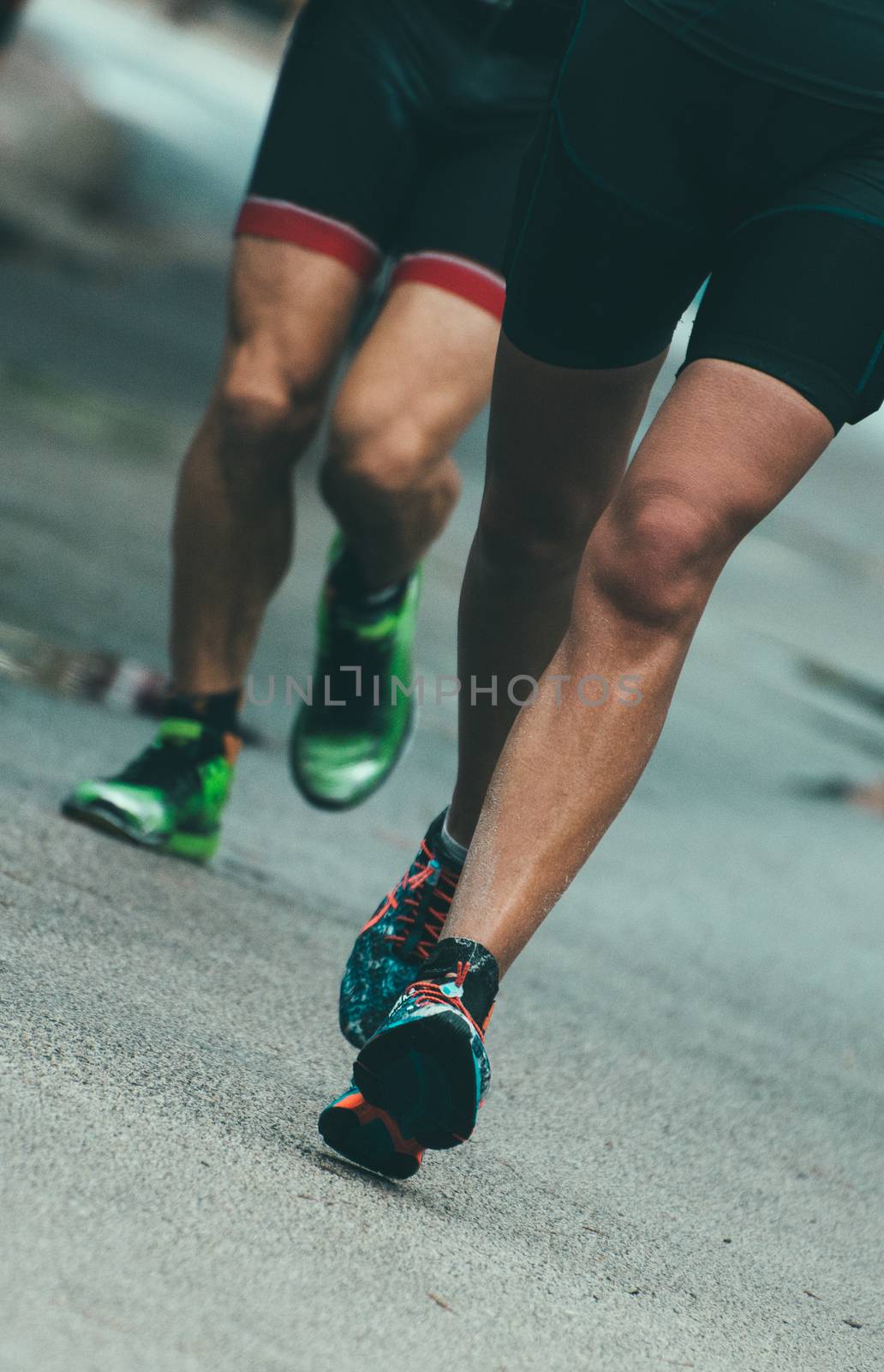 Male runners on the city road. by dmitrimaruta