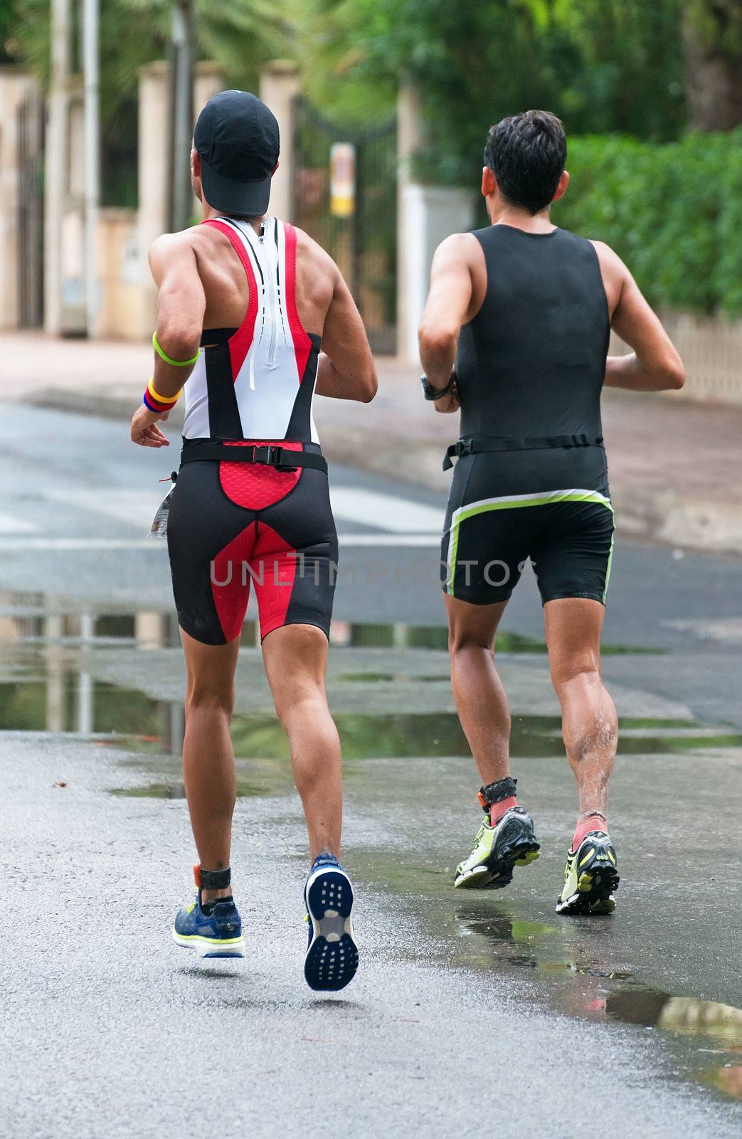 Male runners on the city road. Back view.