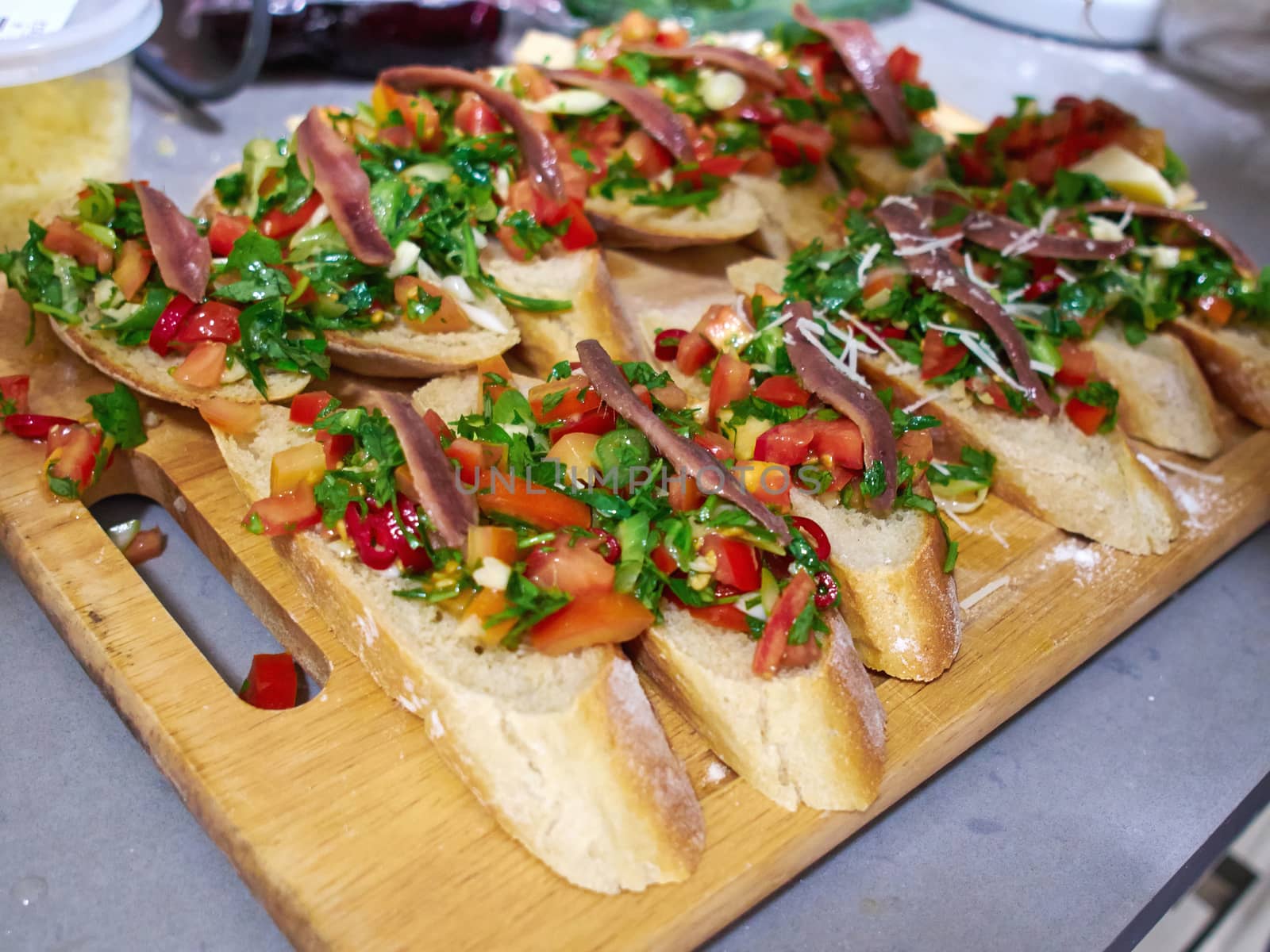 Typical classical Italian Bruschetta with tomatoes, herbs and oil on toasted garlic cheese bread on a wooden tray