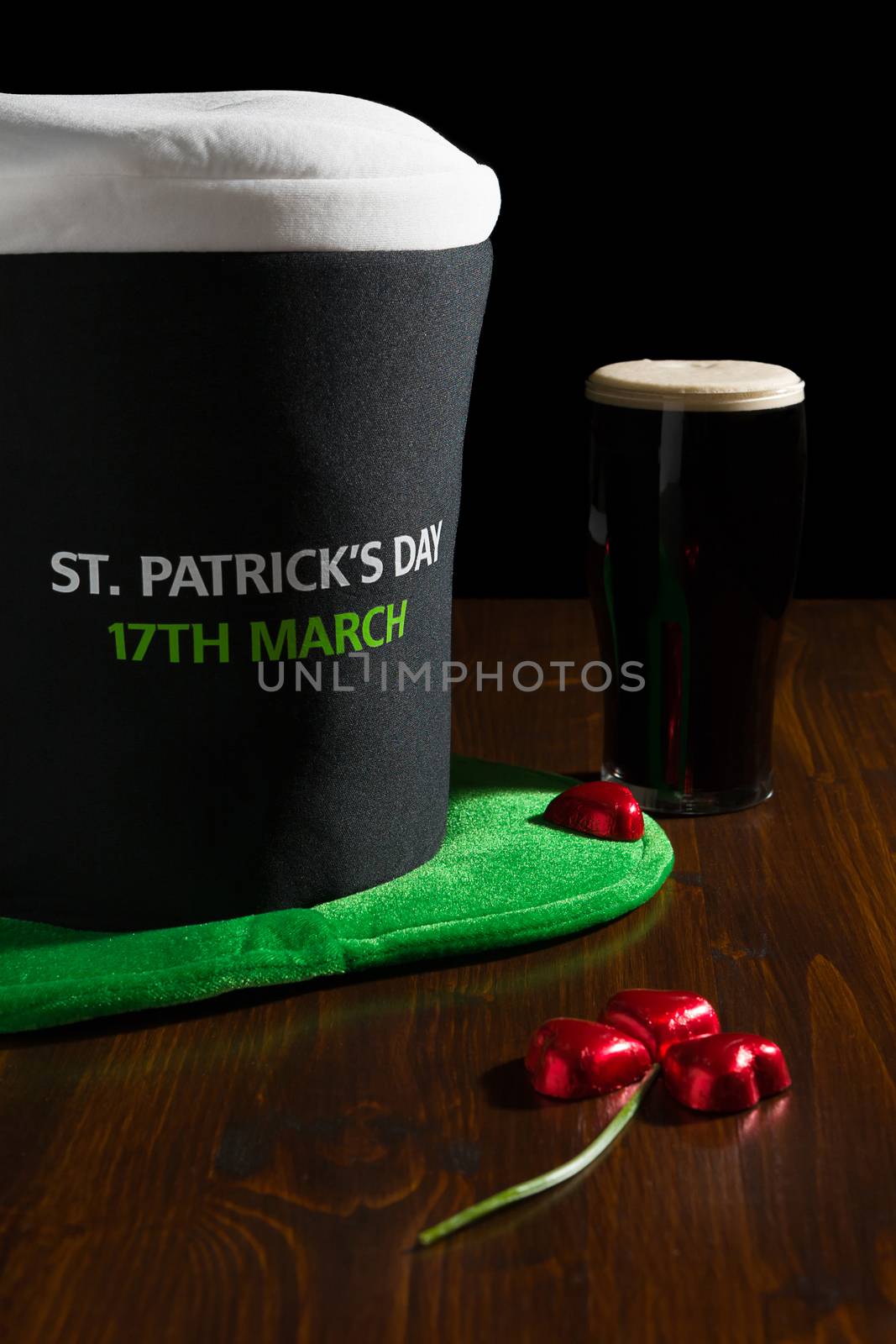 St Patrick day with a pint of black beer, hat and shamrock over a table and black background