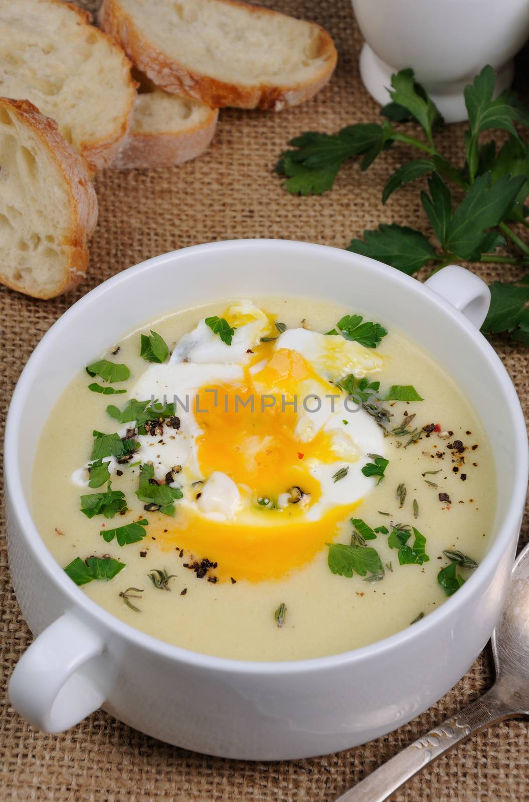 potato cream soup with bacon and poached eggs, herbs, spices