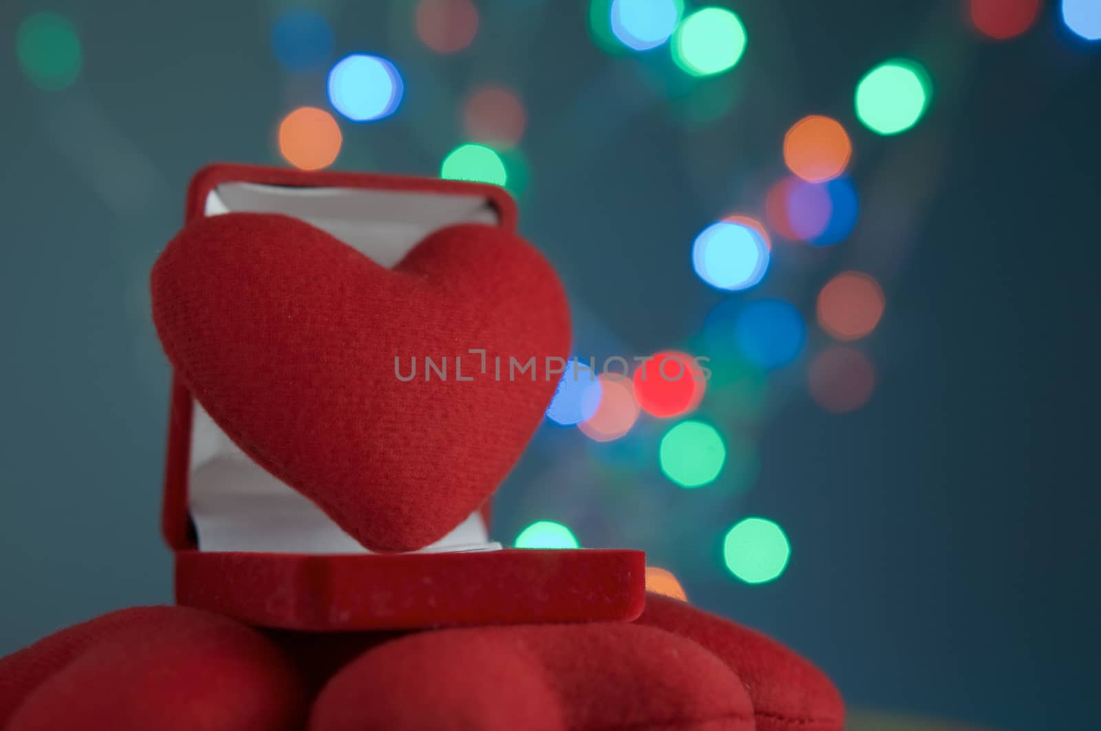 Red heart in velvet ring box have defocused of colorful glitter or bokeh circle at night as background.