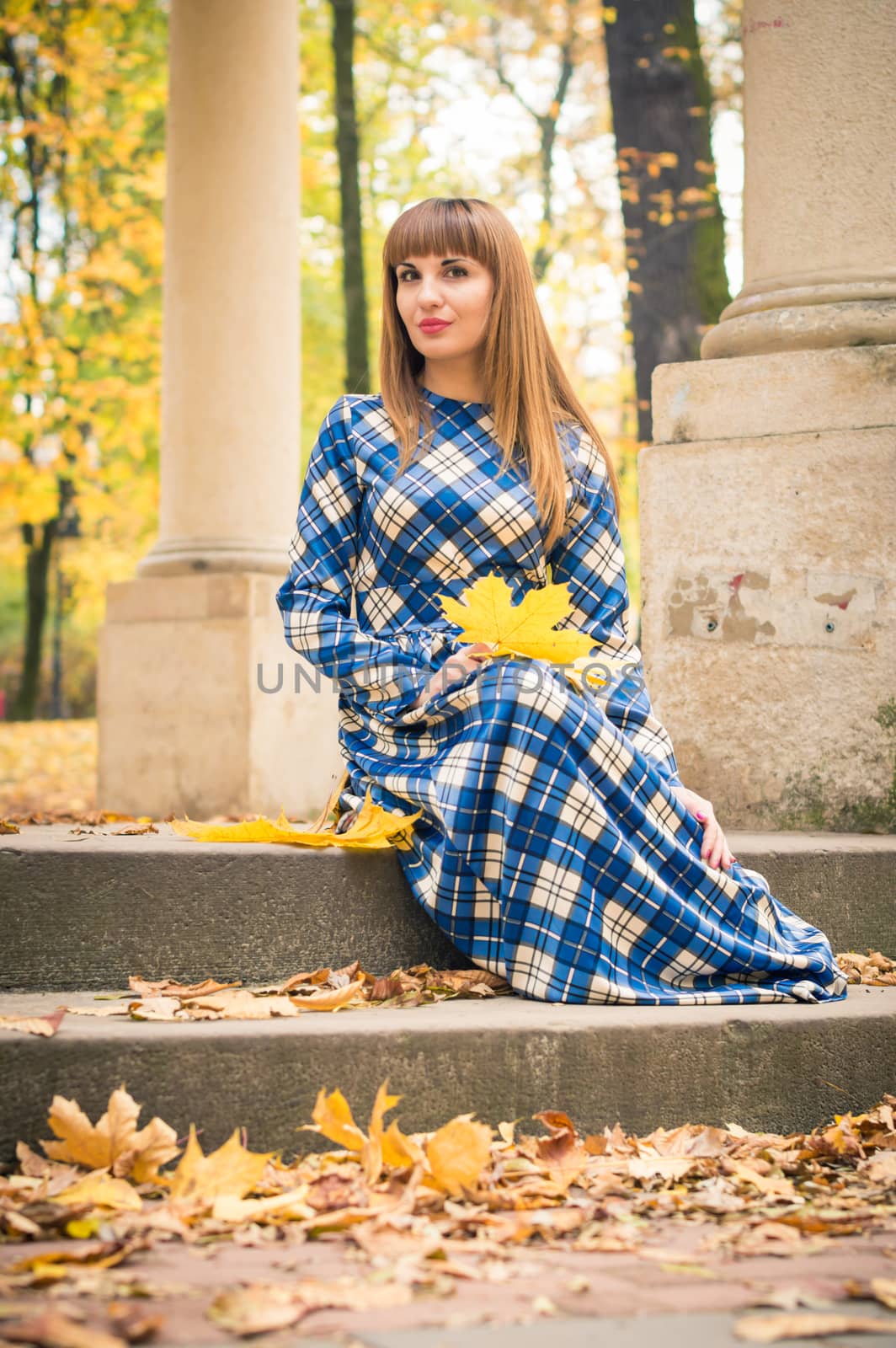 beautiful, dreamy girl with long straight hair in a blue long dress in the park in autumn