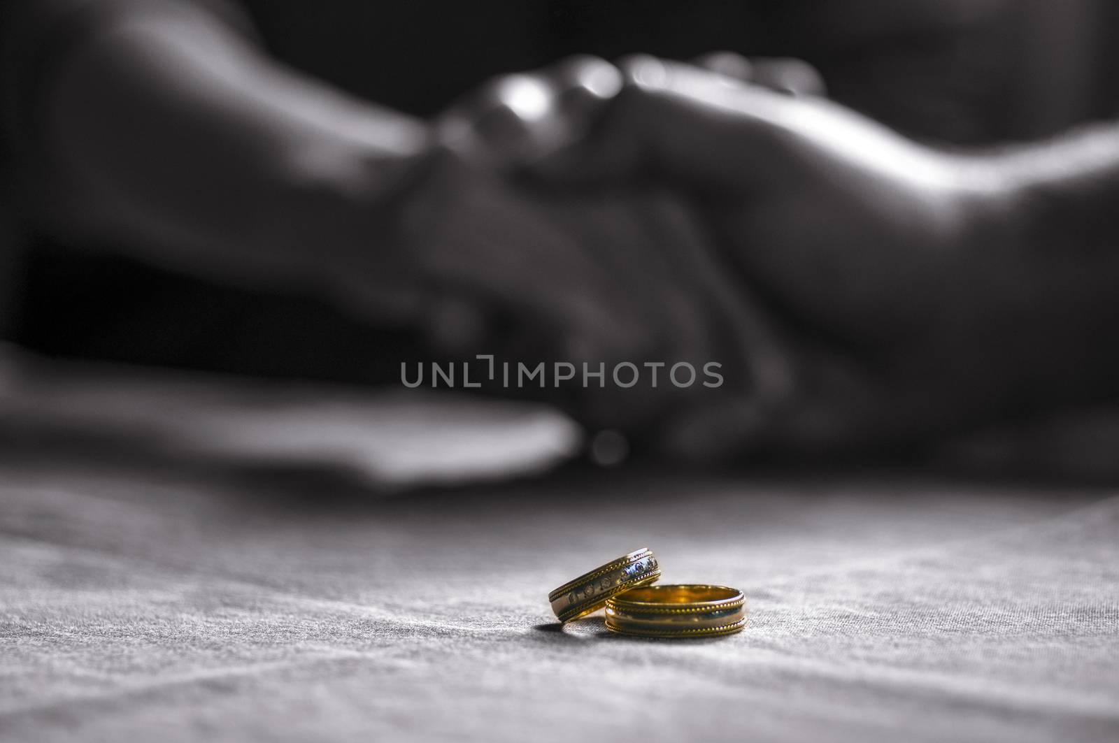 Love, Valentine`s day and wedding concept. Two wedding rings with man and woman hands blurred in the background. Selective focus
