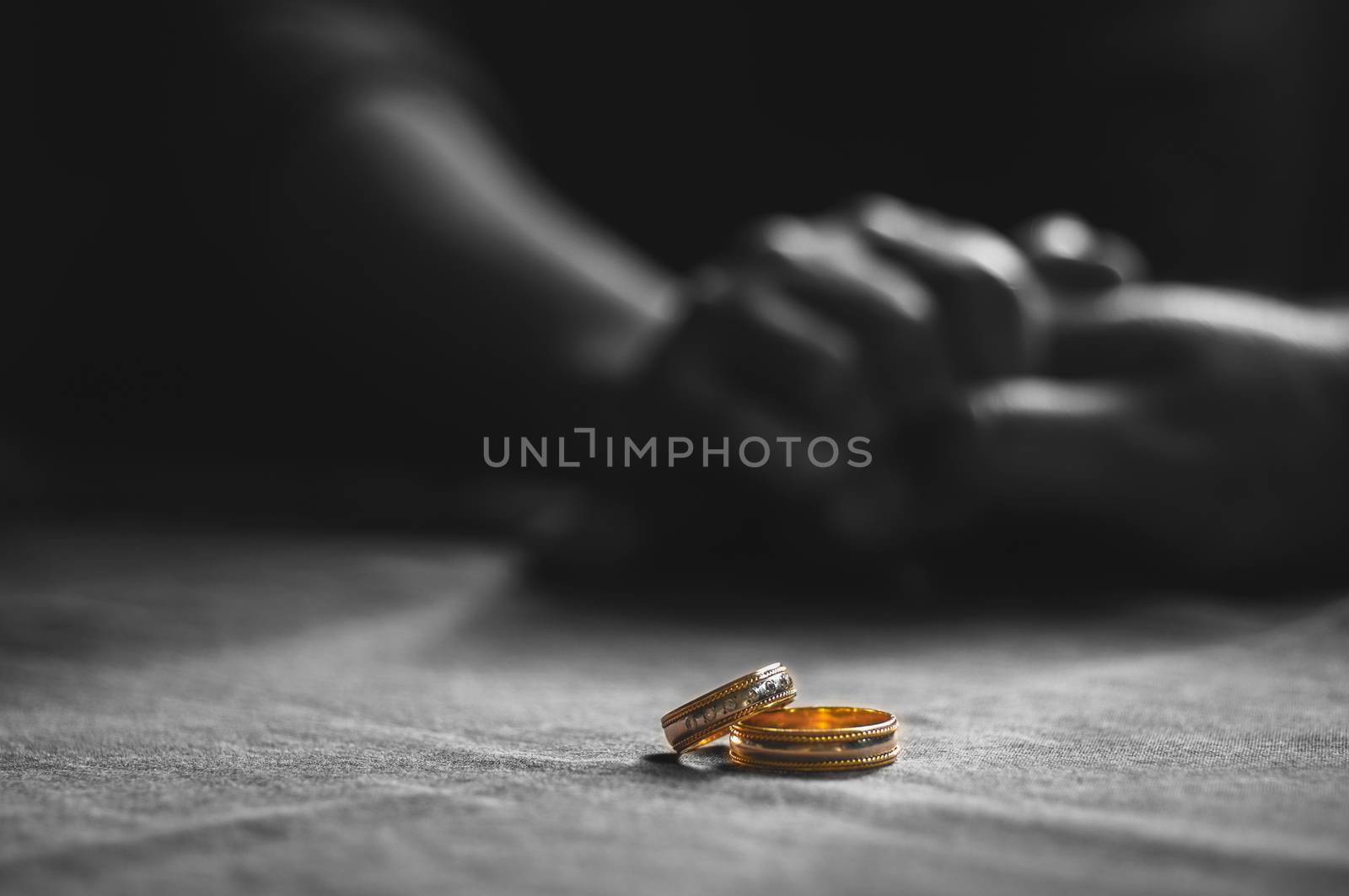 Love, Valentine`s day and wedding concept. Two wedding rings with man and woman hands blurred in the background. Selective focus by Zeferli