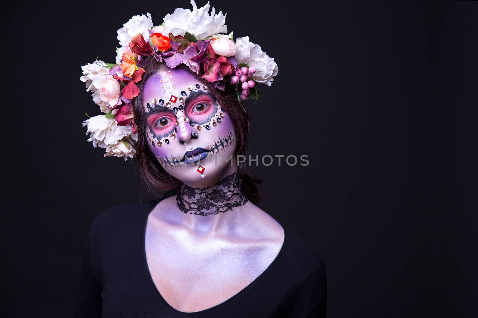 Fashion portrait of a beautiful Halloween model with creative make up,  rhinestones and wreath of flowers