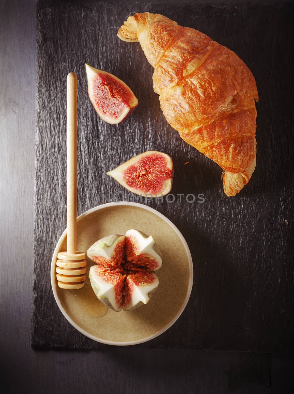 Croissant and figs on a stone plate.