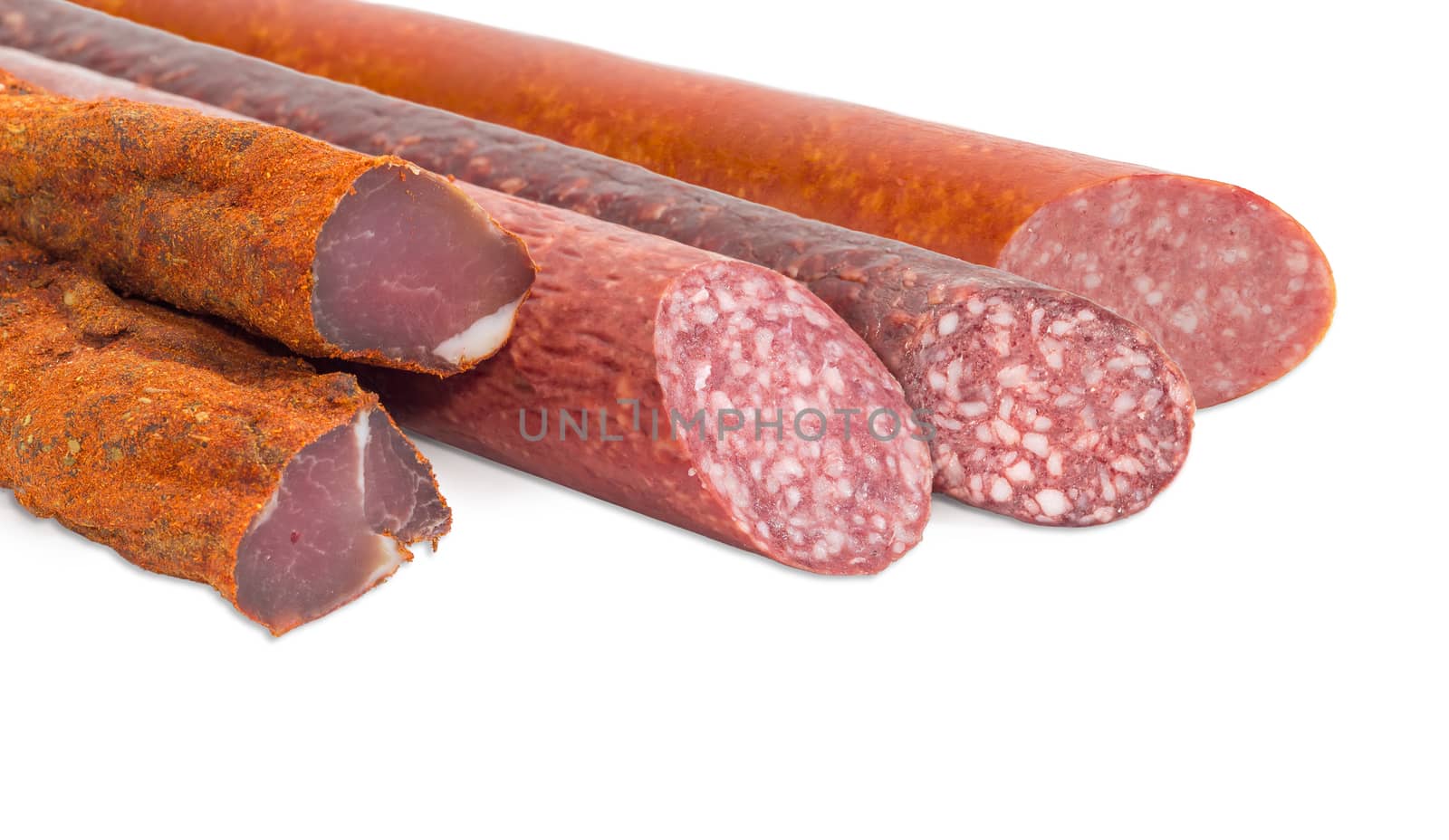 Fragment of the partly sliced pieces of the dried pork tenderloin and the different cooked smoked and dry smoked sausages closeup on a light background  
