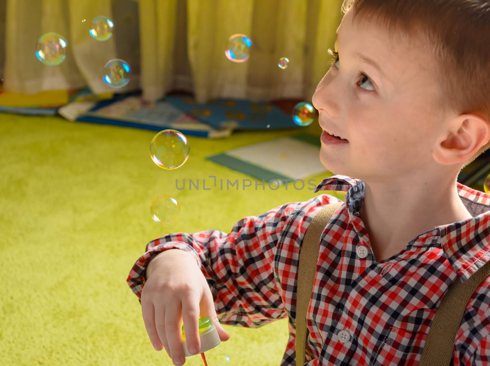 a child inflates soap bubbles and smiling