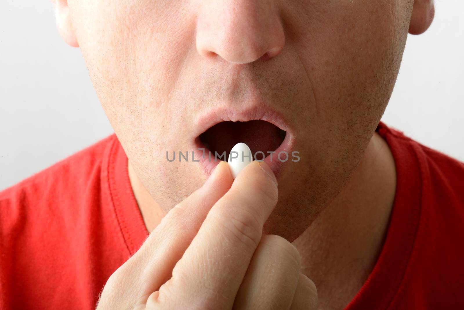 close portrait of a man taking a pill