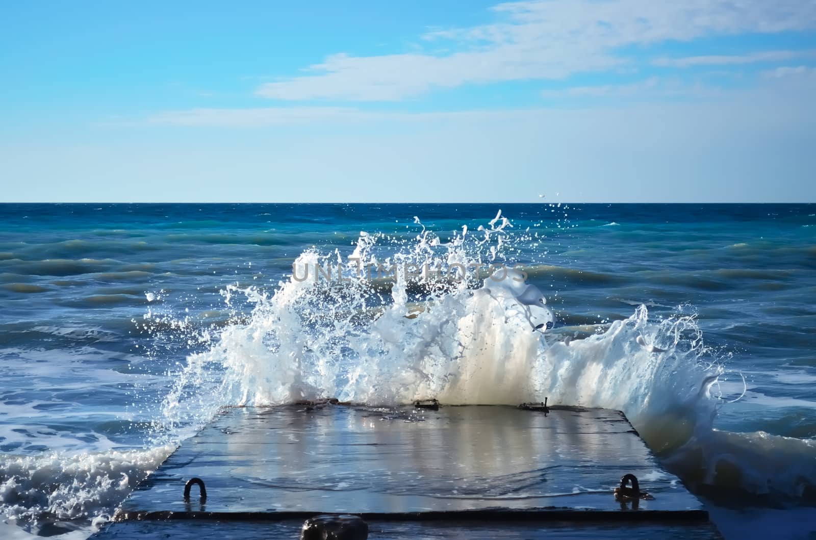 Powerful waves of the sea foam, breaking the concrete pier