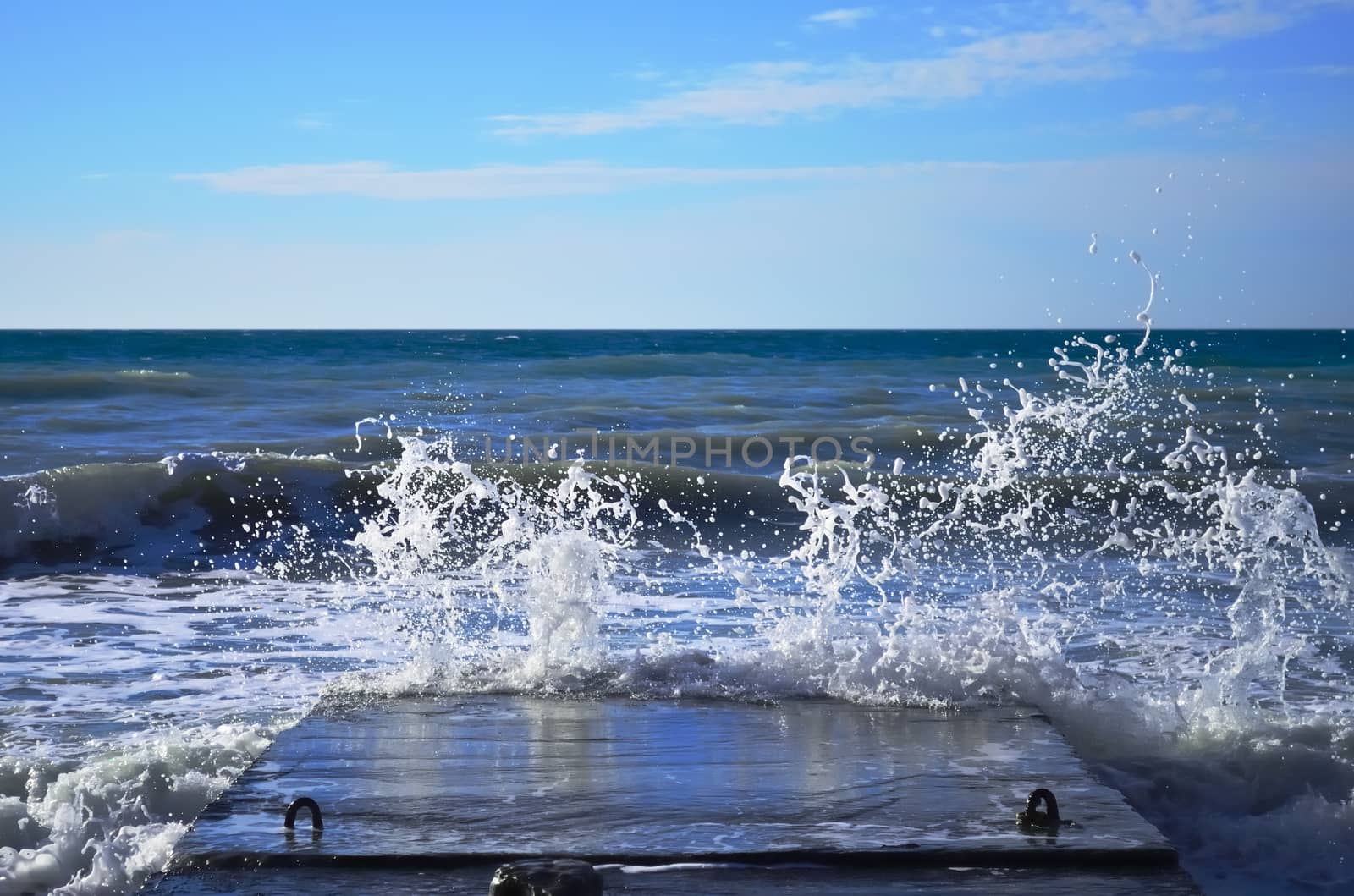 Powerful waves of the sea foam, breaking the concrete pier