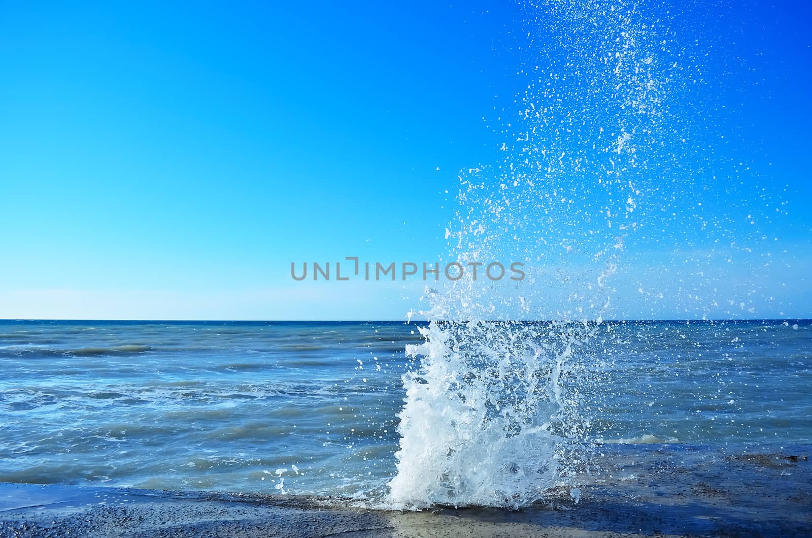 Powerful waves of the sea foam, breaking the concrete pier