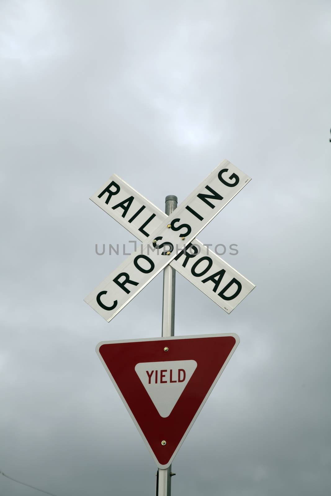 Close up of a railroad crossing and yield sign against a stormy sky