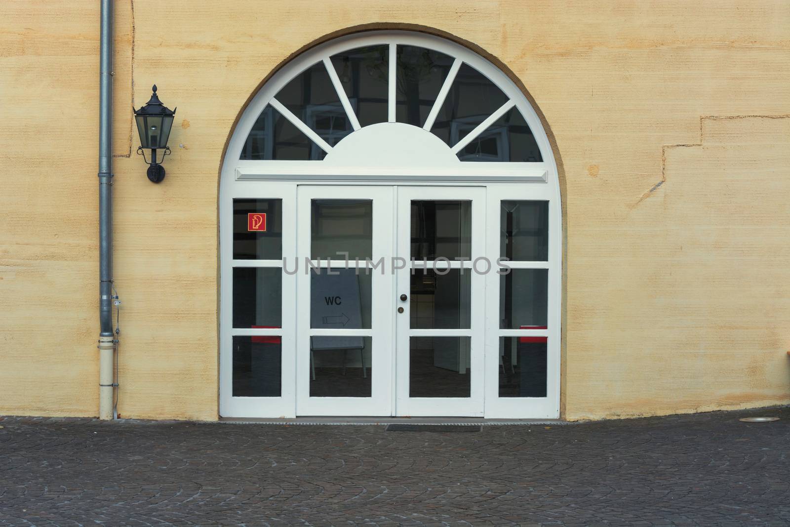 New large round arch door with rungs in a yellow plastered house wall.