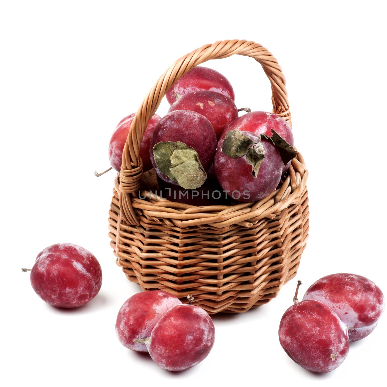 Arrangement of Frozen Sweet Red Plums with Leafs in Wicker Basket isolated on White background