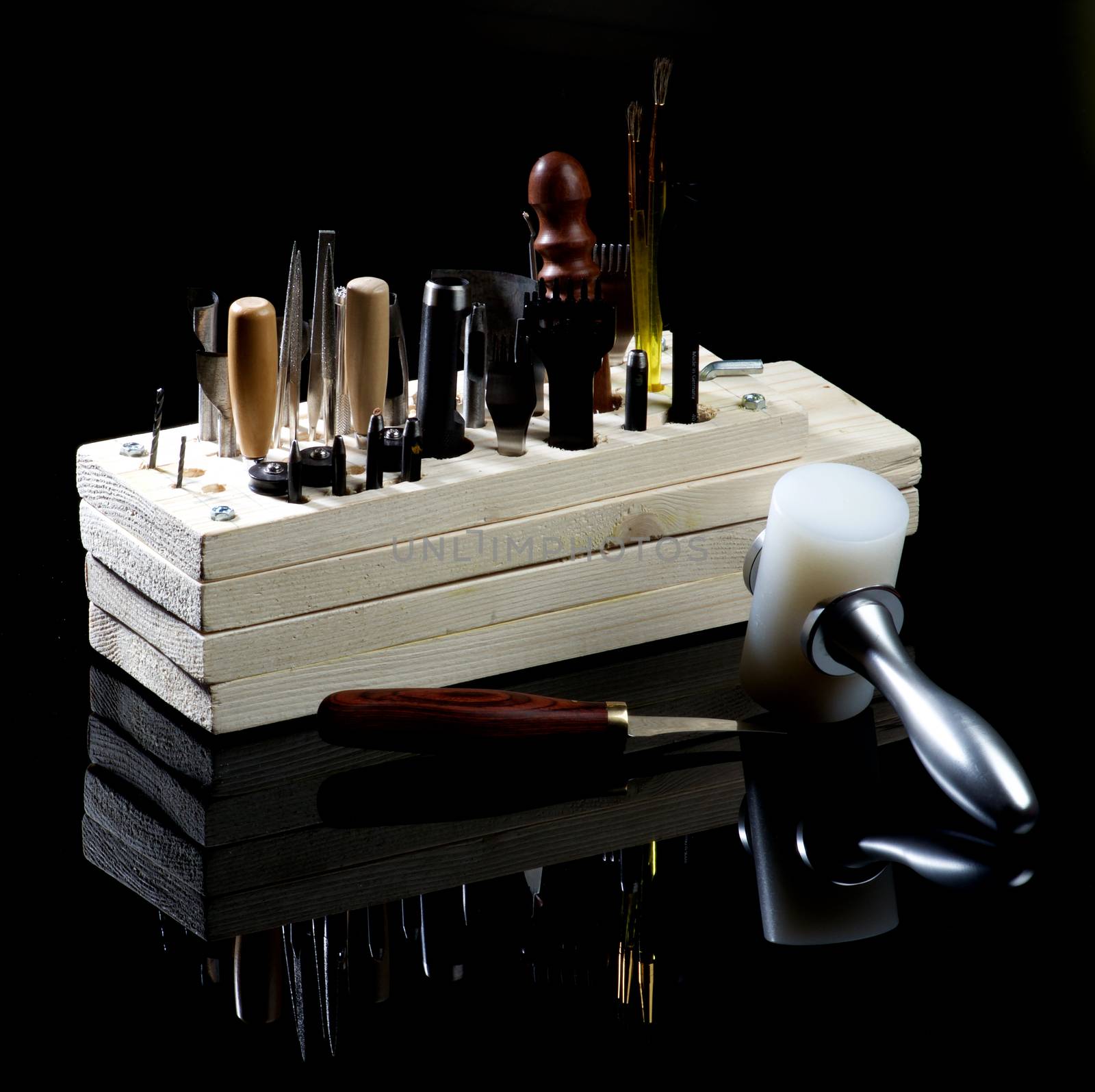 Arrangement of Various Tanneries Tools for Cutting and Piercing of Leather in Wooden Box with Reflection on Black Shiny background