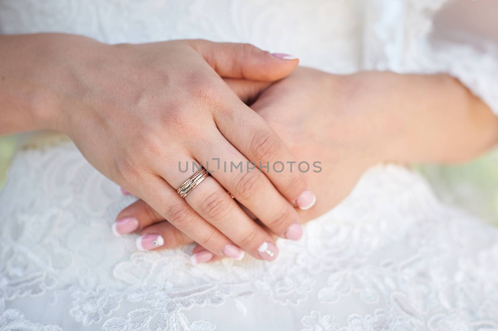 bride hand with a wedding ring on the background of dress.