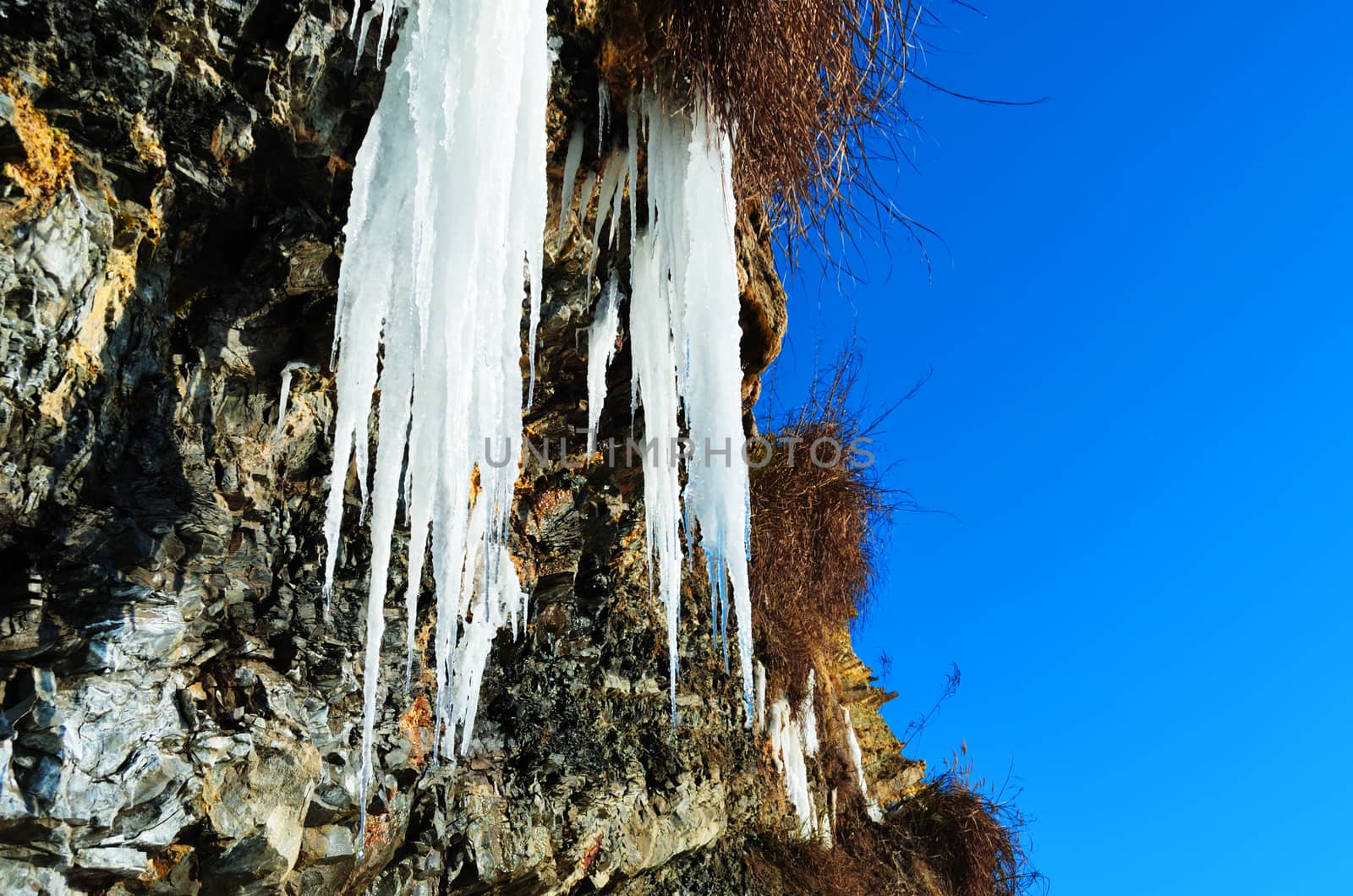 Steep rock with a frozen waterfall near the sea