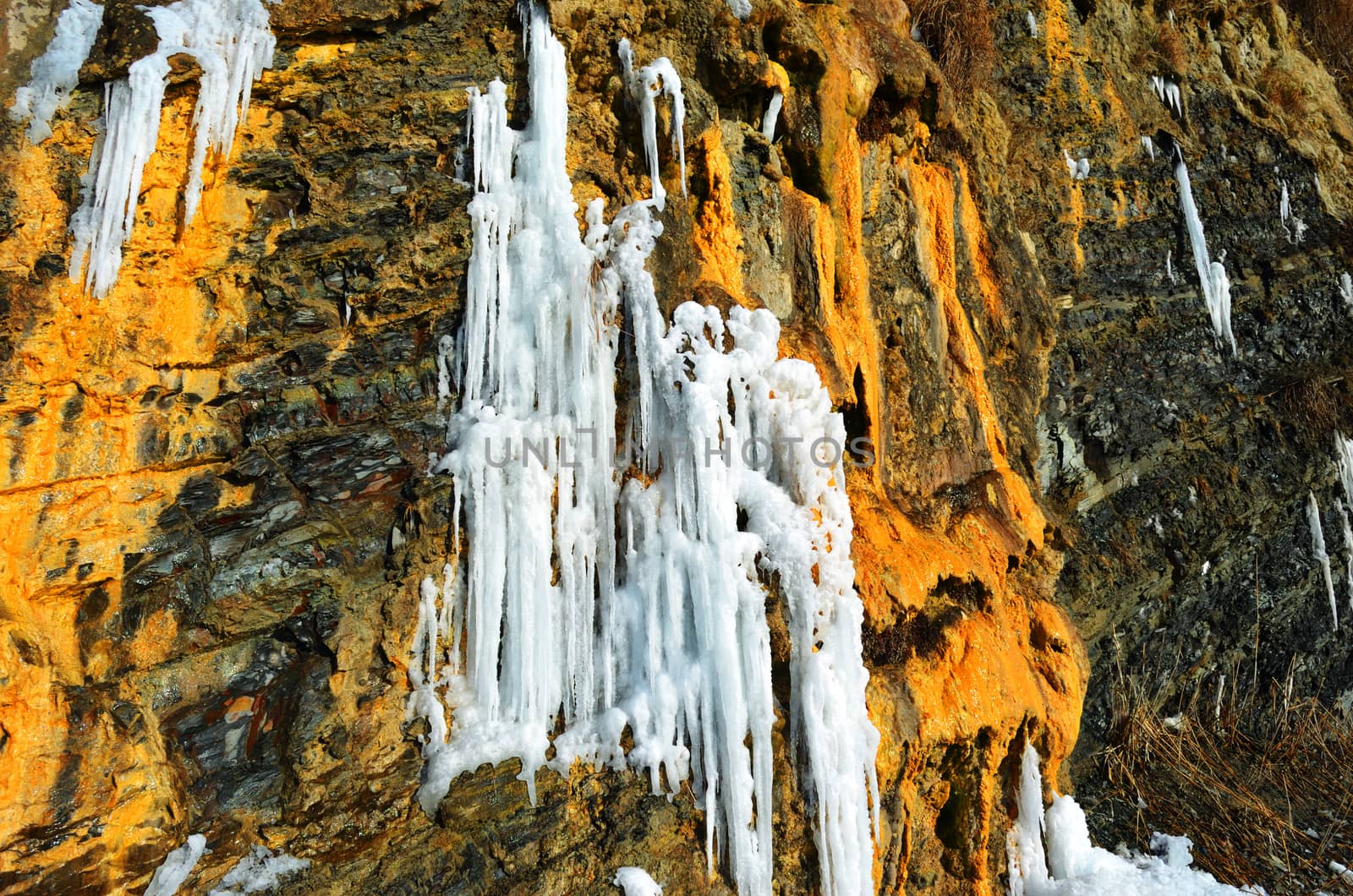 Steep rock with a frozen waterfall near the sea