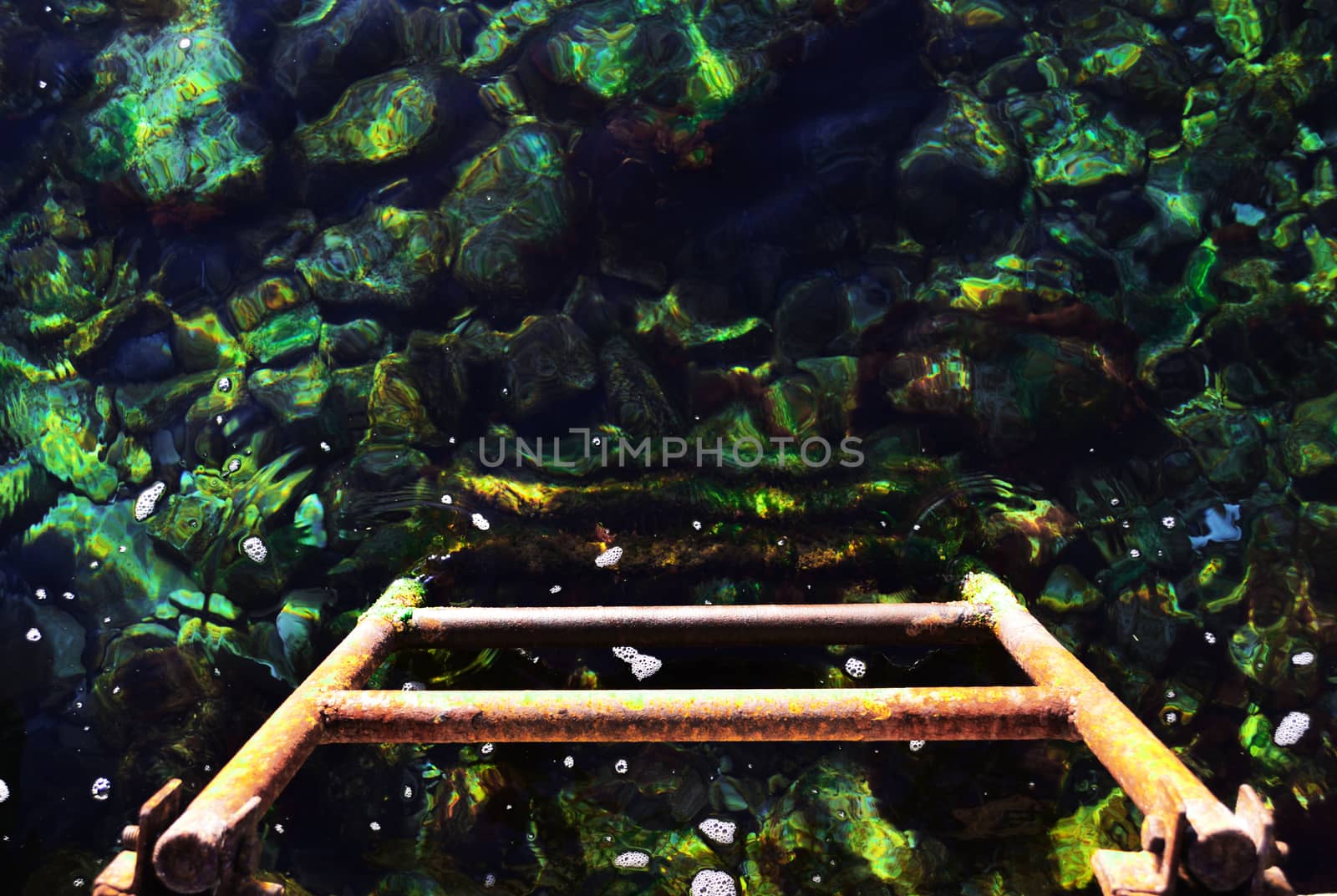 Iron stairs, disappearing into the clear sea water and rocks on the bottom