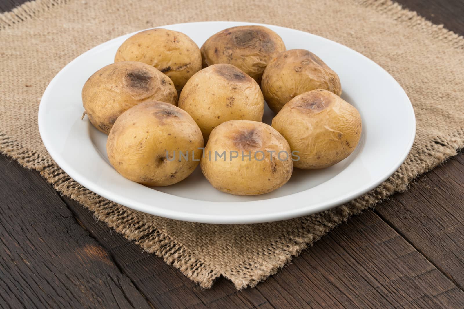 baked potatoes in a white plate on old wooden table by DGolbay