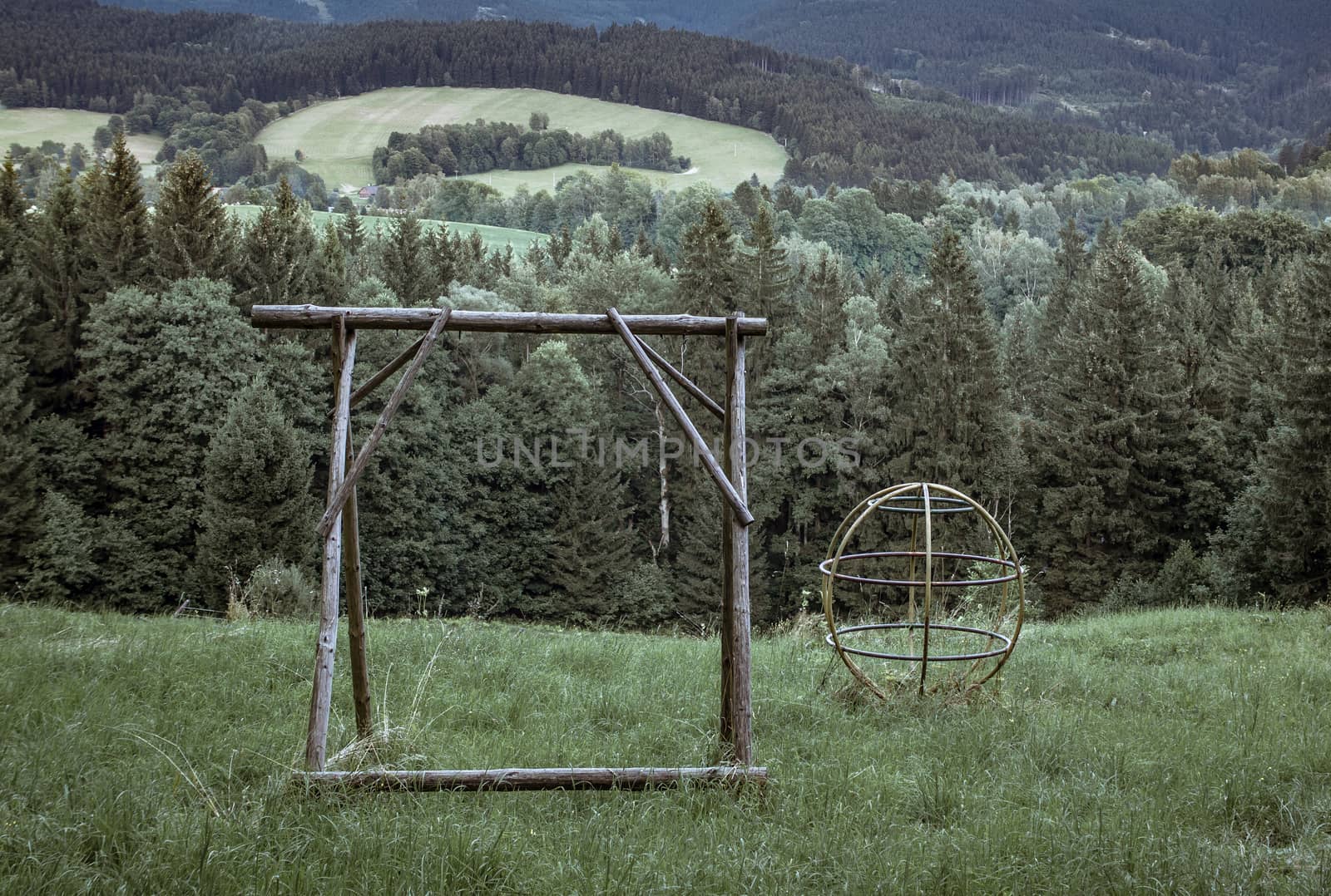 Abandoned playground with overgrown grass in the forest in cold colours, lonelines abandonment neglect, lost childhood