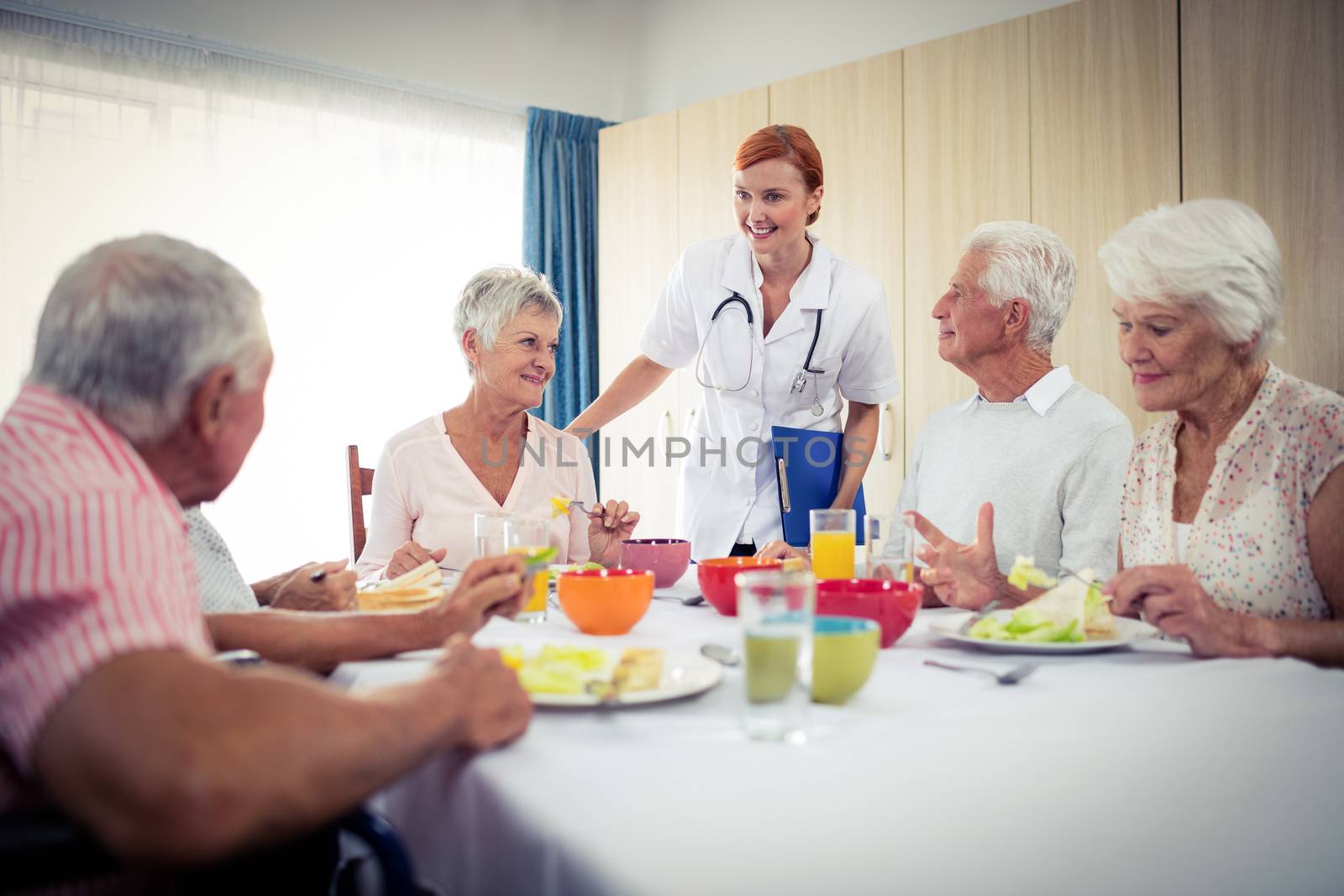 Pensioners at lunch with nurse by Wavebreakmedia