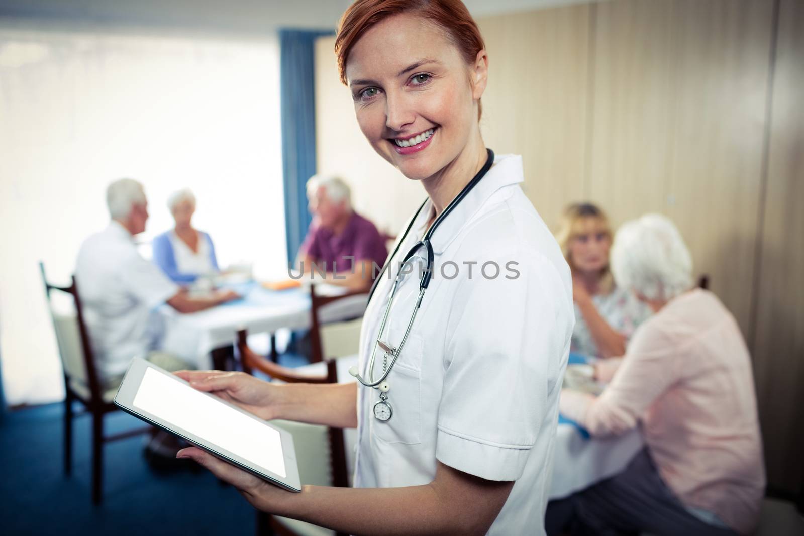 Portrait of a nurse with tablet computer in the retirement house