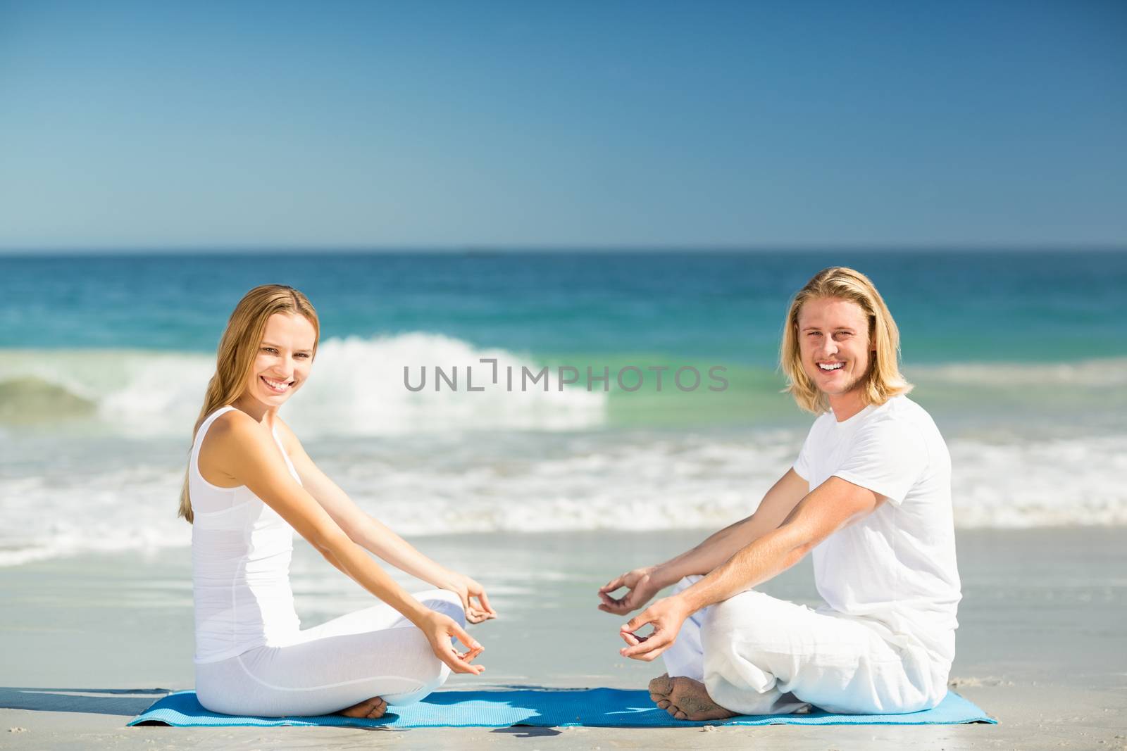 Portrait of man and woman performing yoga on beach