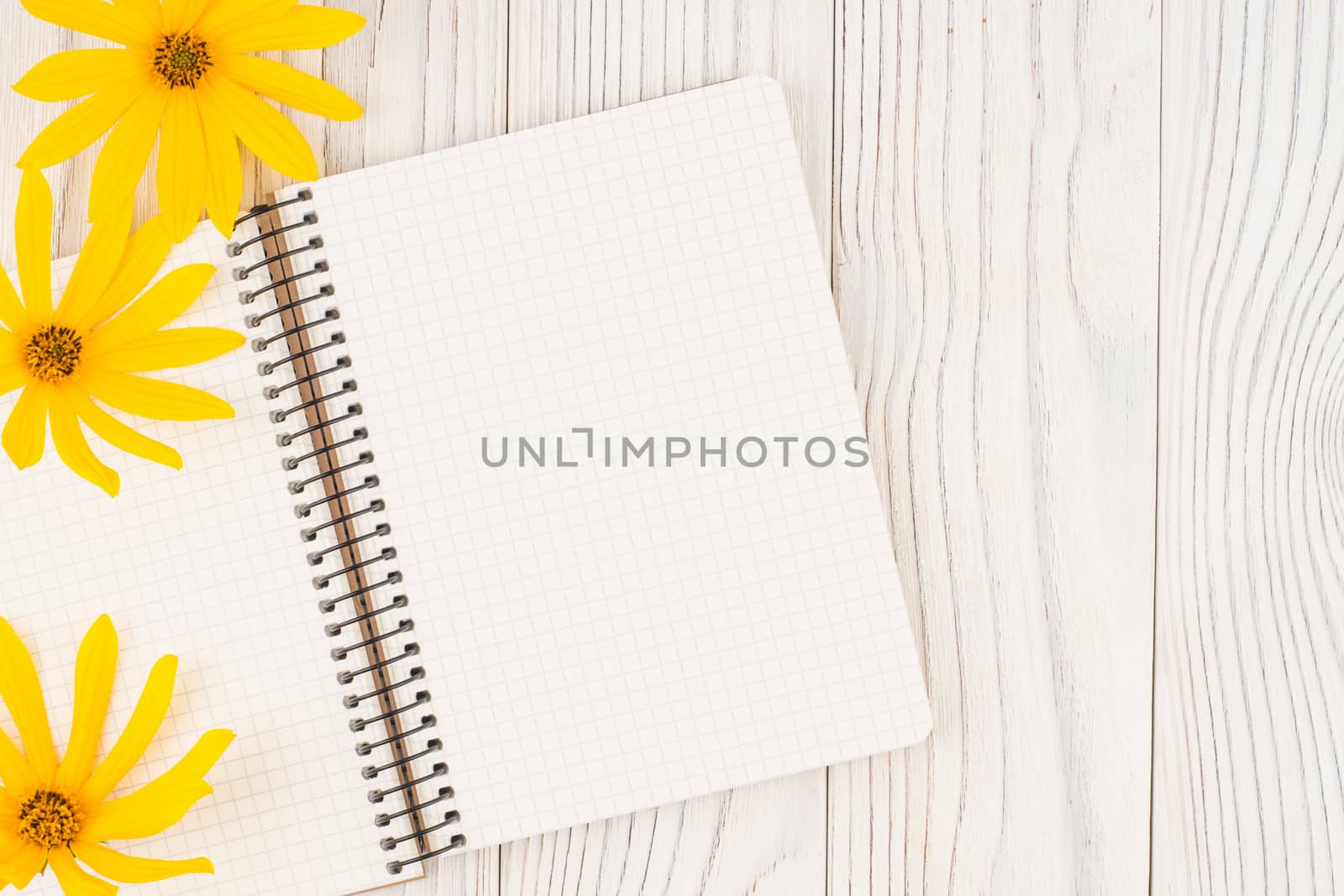 Notebook with yellow wild flowers on  old wooden table. Top view.