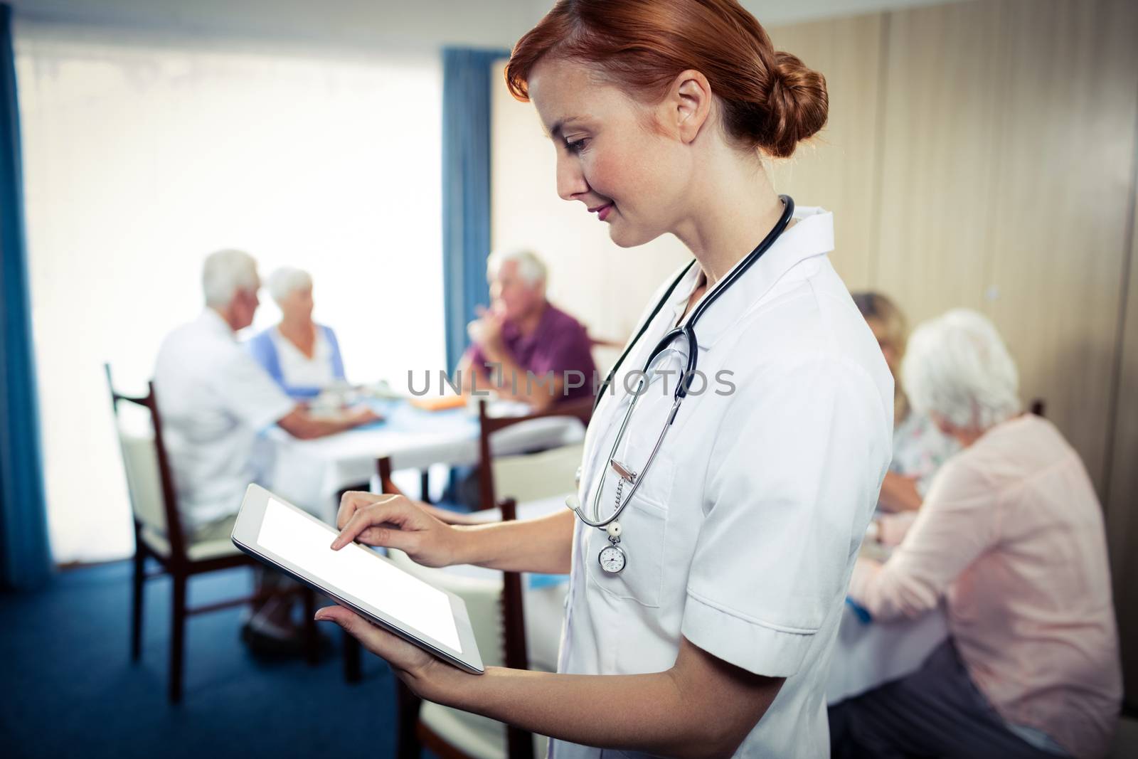 Portrait of a nurse with tablet computer in the retirement house