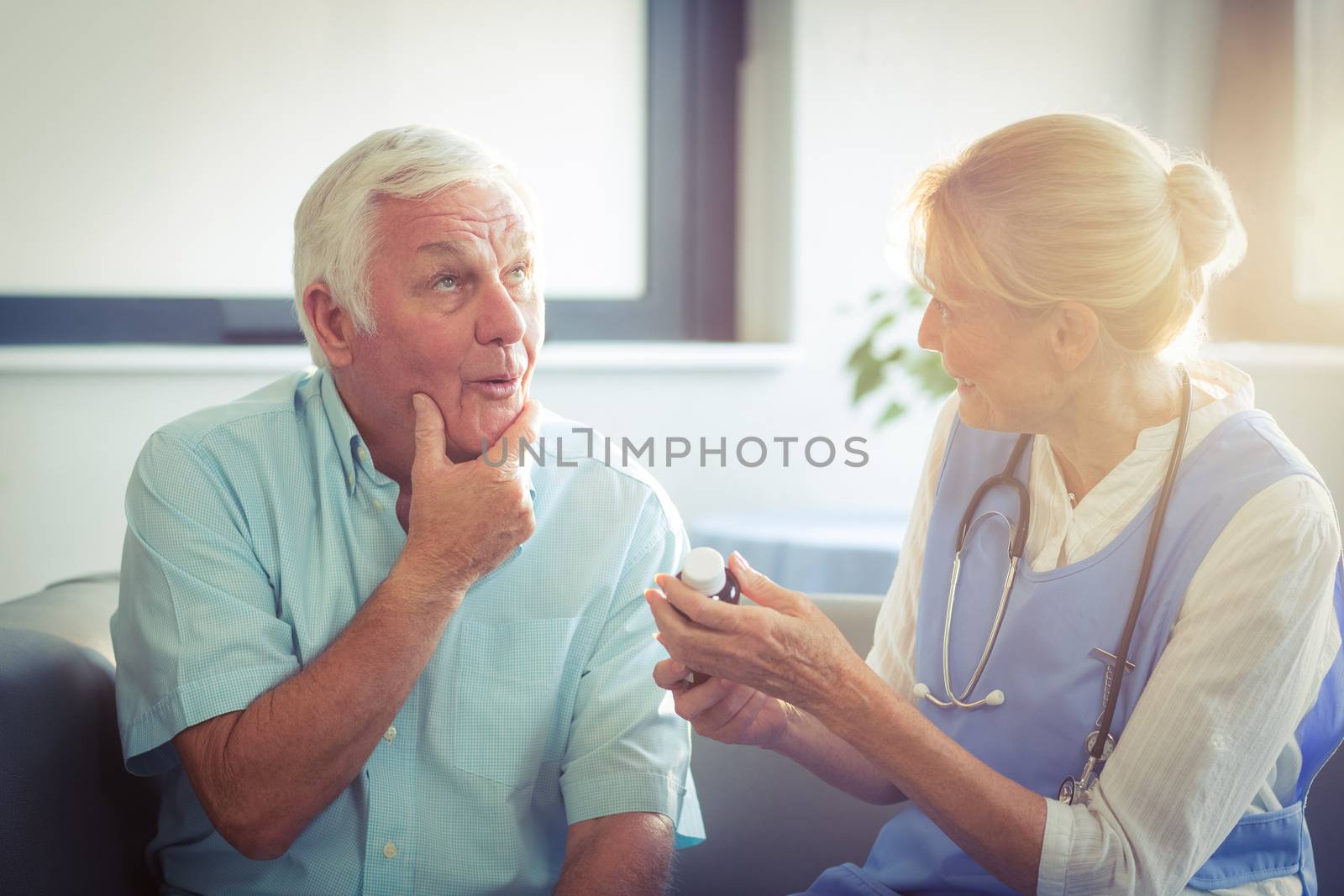Senior man talking with female doctor in living room