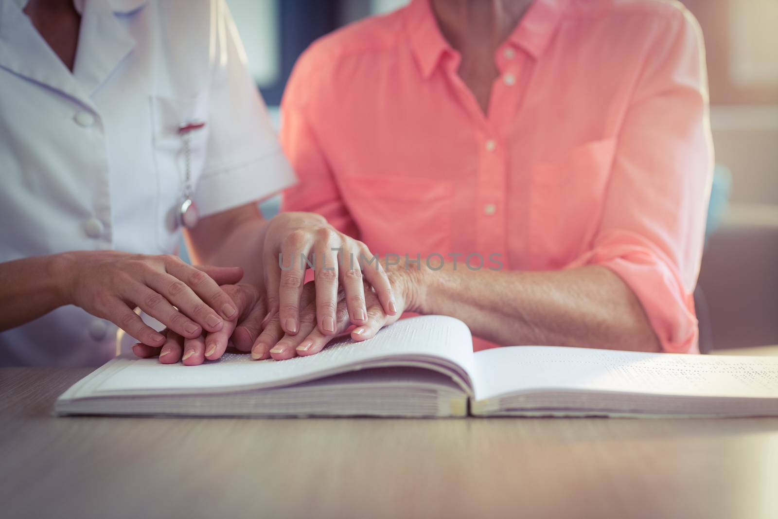 Female nurse helping patient reading the braille book by Wavebreakmedia