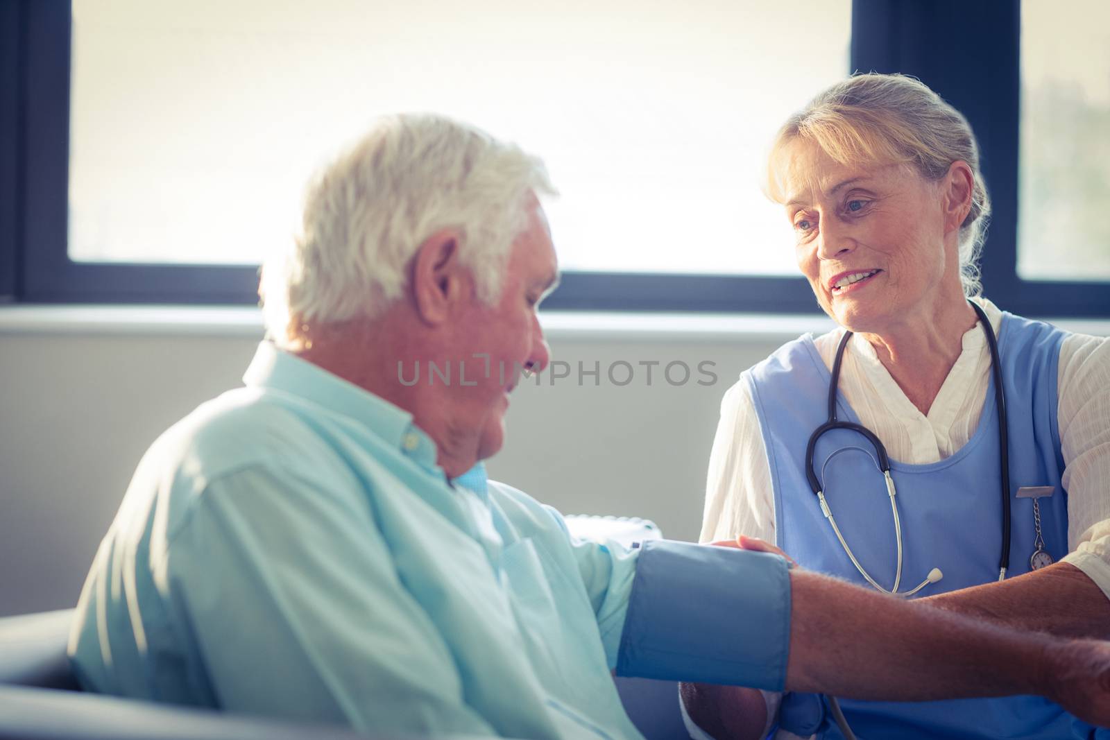 Female doctor checking blood pressure of senior man at home