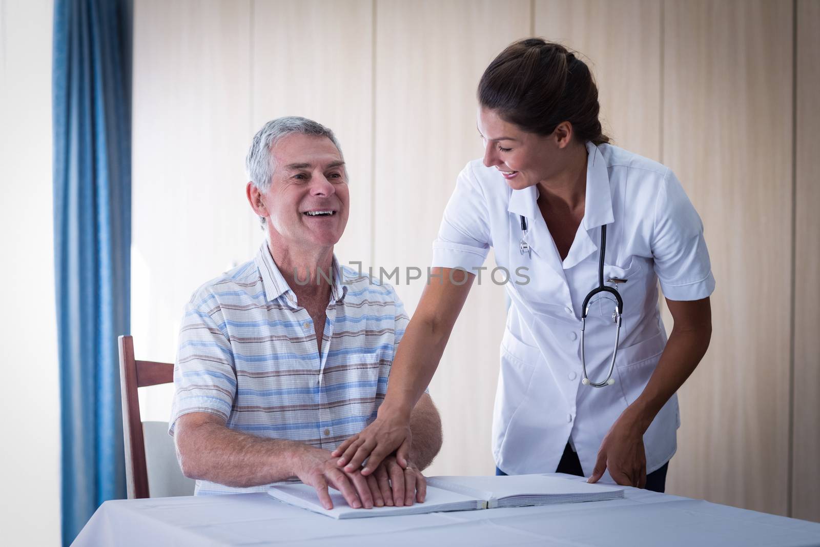 Female doctor helping patient in reading the braille book at home