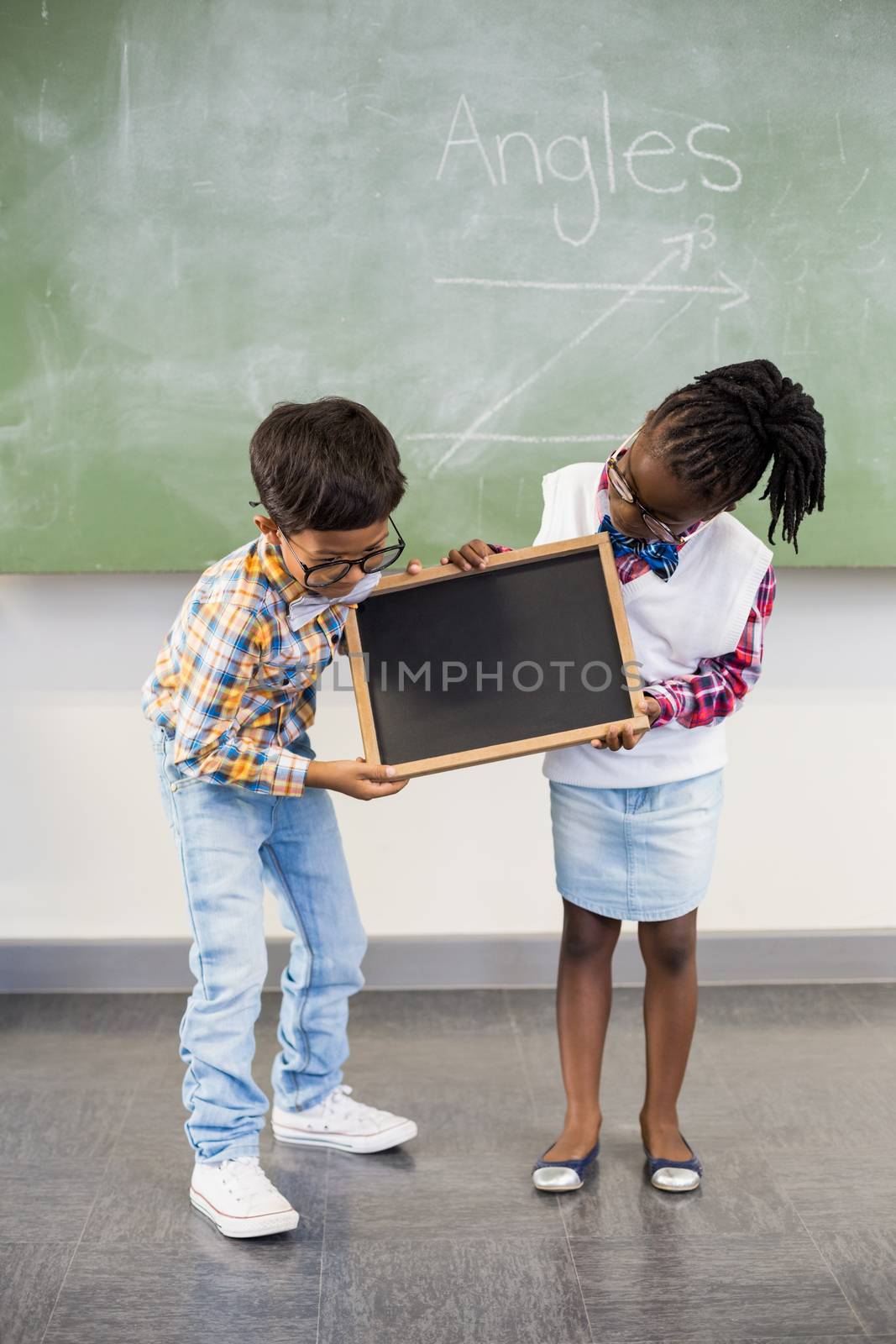 School kids looking at slate in classroom at school